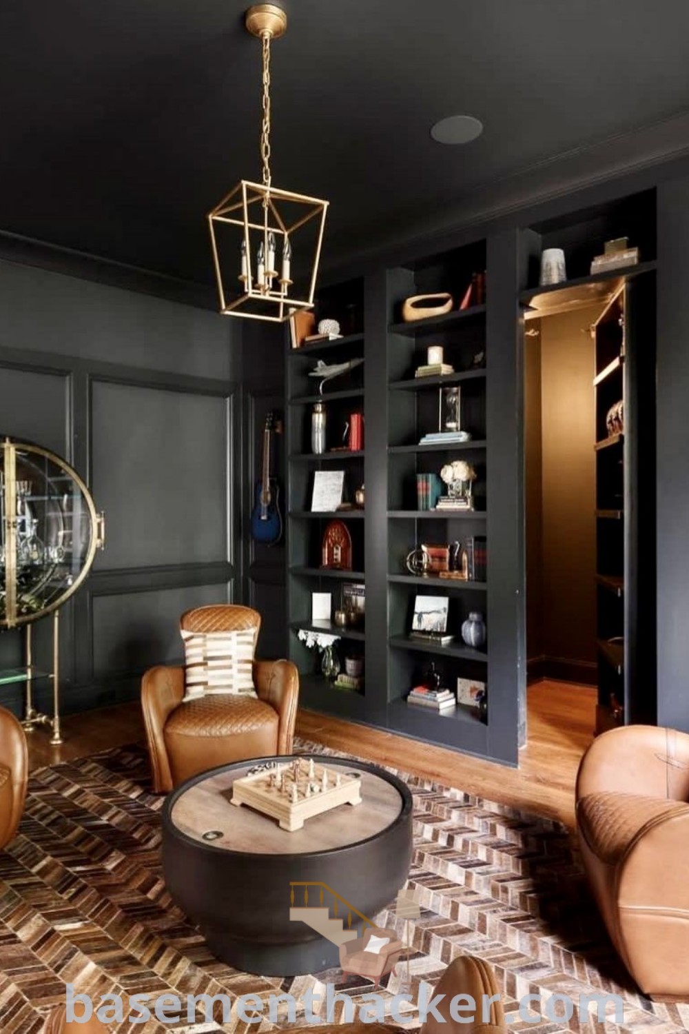 A cozy living room featuring a cocktail room design with black walls, stylish bar furniture, and bookshelves full of books, perfect for creating a moody lounge atmosphere for ultimate entertaining. Explore more stylish bonus room design ideas at basementhacker.com.
