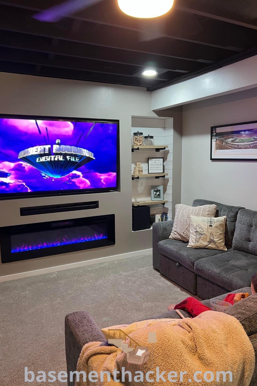 A cozy living room in a split level basement filled with stylish furniture and a flat screen TV mounted on the wall, showcasing innovative ideas for designing a functional space. Discover the best basement remodeling ideas for your home at basementhacker.com.