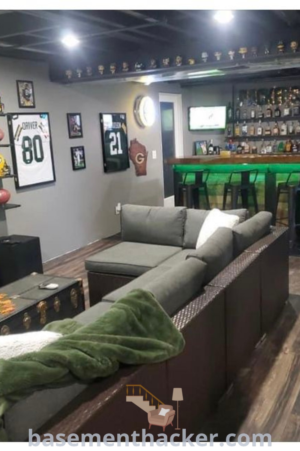 A lively living room filled with furniture, vibrant pictures, and a stylish bar, reflecting innovative basement makeover ideas for a cozy game room. This scene exemplifies the best man cave designs, featuring sports cave ideas and smart usage of space, ideal for the ultimate entertaining experience. Discover more at basementhacker.com.