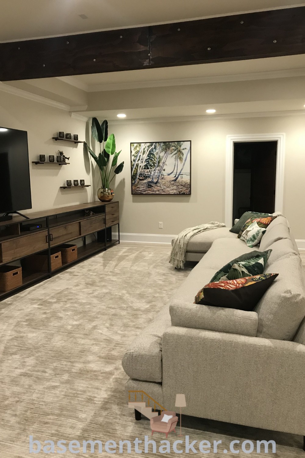 A contemporary basement living room filled with stylish furniture and a flat-screen TV mounted on the wall, showcasing innovative basement designs and functional layout ideas for a cozy and organized home. For the ultimate entertaining experience and creative basement makeover ideas, visit basementhacker.com.