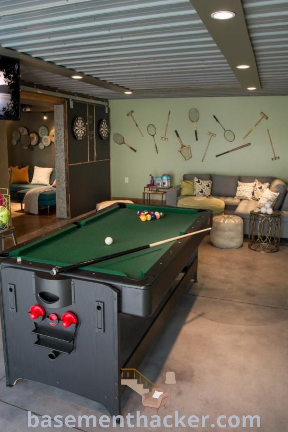 A stylish game room featuring a pool table, air hockey table, and television, designed for ultimate entertaining. This innovative basement showcases creative ideas for a cozy and organized home, perfect for family fun and game nights. Discover more design inspiration at basementhacker.com.