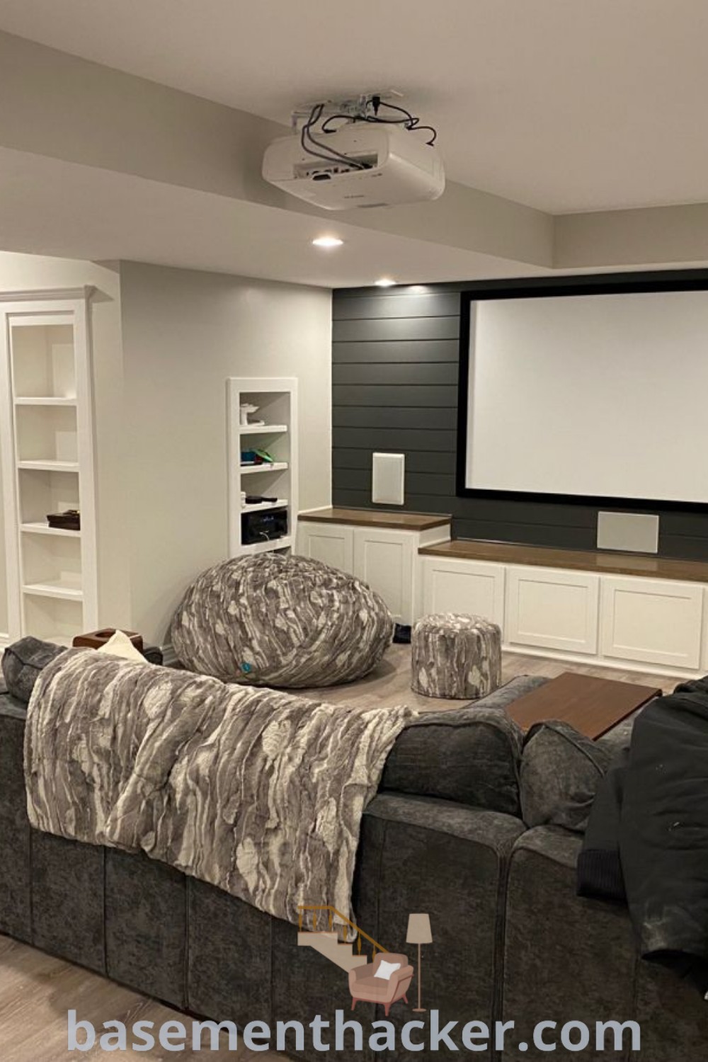 A cozy living room in a basement featuring comfortable furniture, a flat-screen TV mounted on the wall, and design ideas for a stylish and functional home. This space offers innovative basement makeover ideas perfect for ultimate entertaining and family enjoyment. Explore more at basementhacker.com.