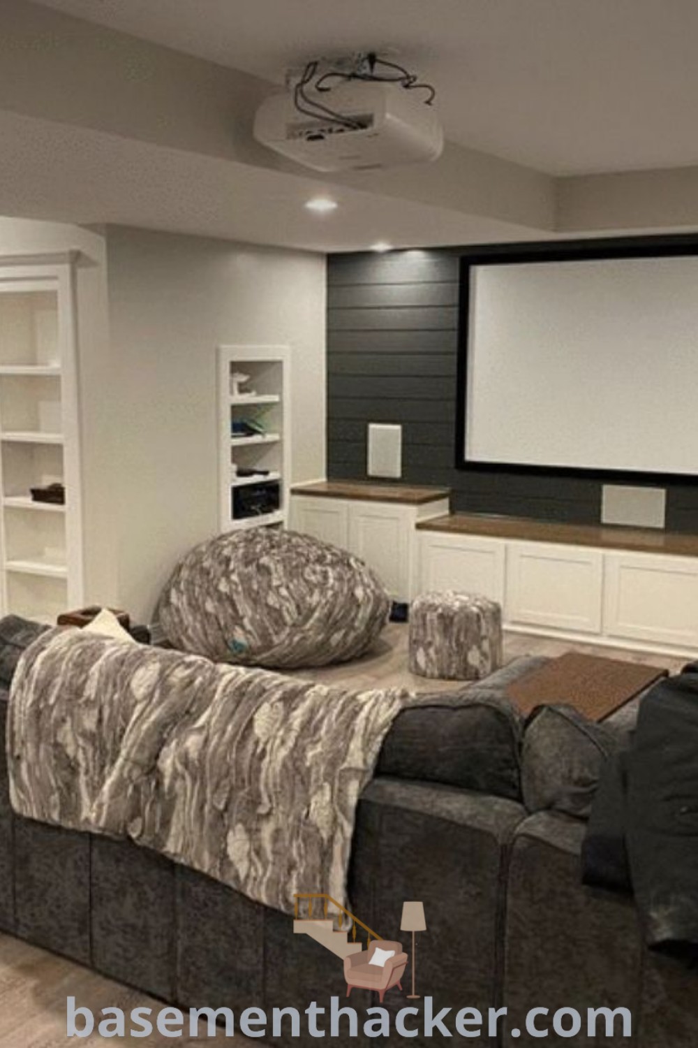 A stylish living room in a basement featuring comfortable furniture, a large projector screen, and clever storage solutions. Showcasing innovative basement makeover ideas for a stunning revamp, this space is designed for ultimate entertaining. Discover more at basementhacker.com.