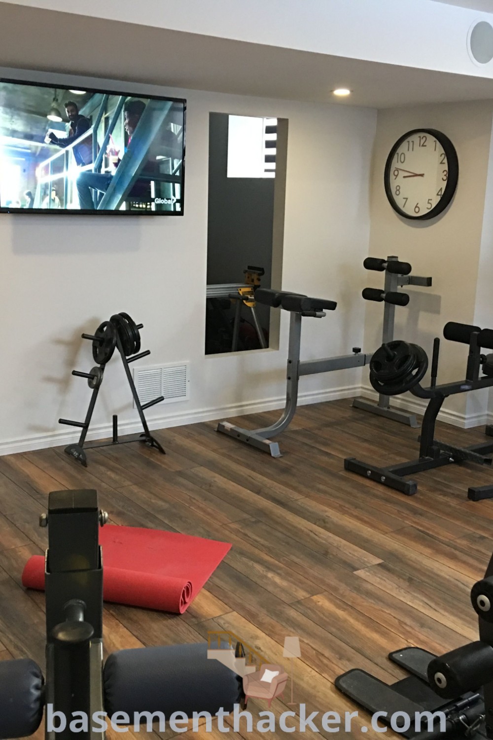 A stylish home gym with various exercise equipment and a flat-screen TV, demonstrating innovative ideas for designing functional spaces. Perfect for gym basement setups, this design showcases the best basement remodeling ideas, appealing to fitness enthusiasts. Discover more at basementhacker.com.