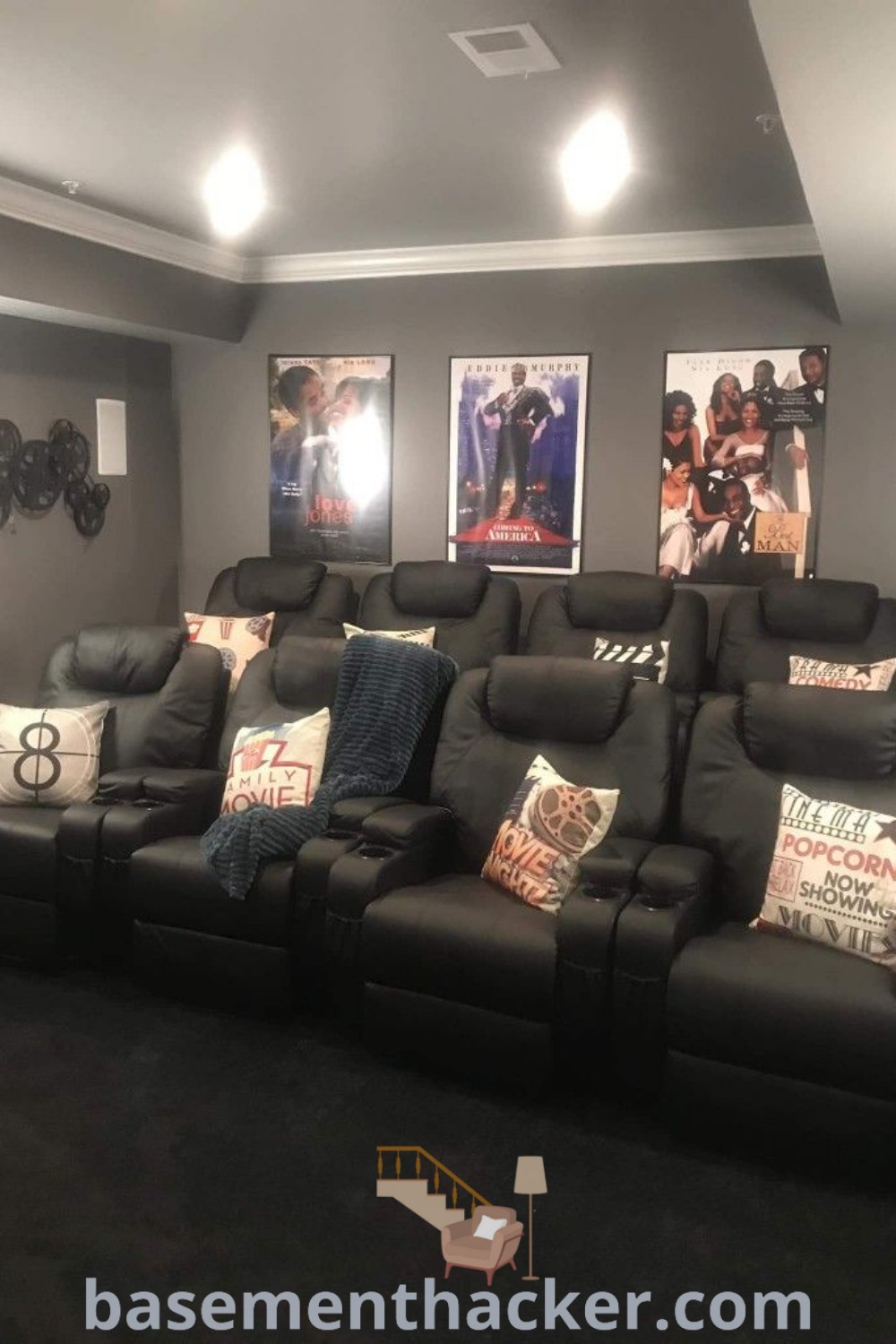 A cozy home theater room with black leather seats and pillows, ideal for ultimate entertaining. Perfect for small theater rooms, this design offers innovative ideas for a stylish and functional home theater experience. Discover more creative basement makeover ideas at basementhacker.com.