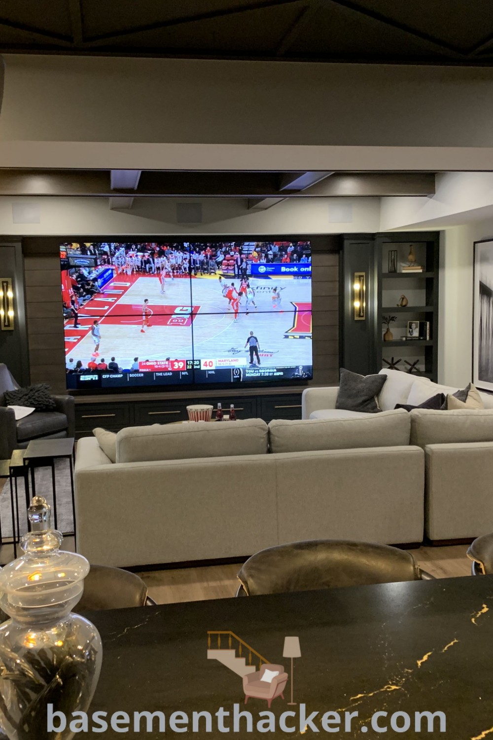 A cozy living room filled with stylish furniture and a flat-screen TV mounted over a fireplace, showcasing innovative ideas for designing an ultimate entertaining space. Find more inspiration for your home’s decor at basementhacker.com.