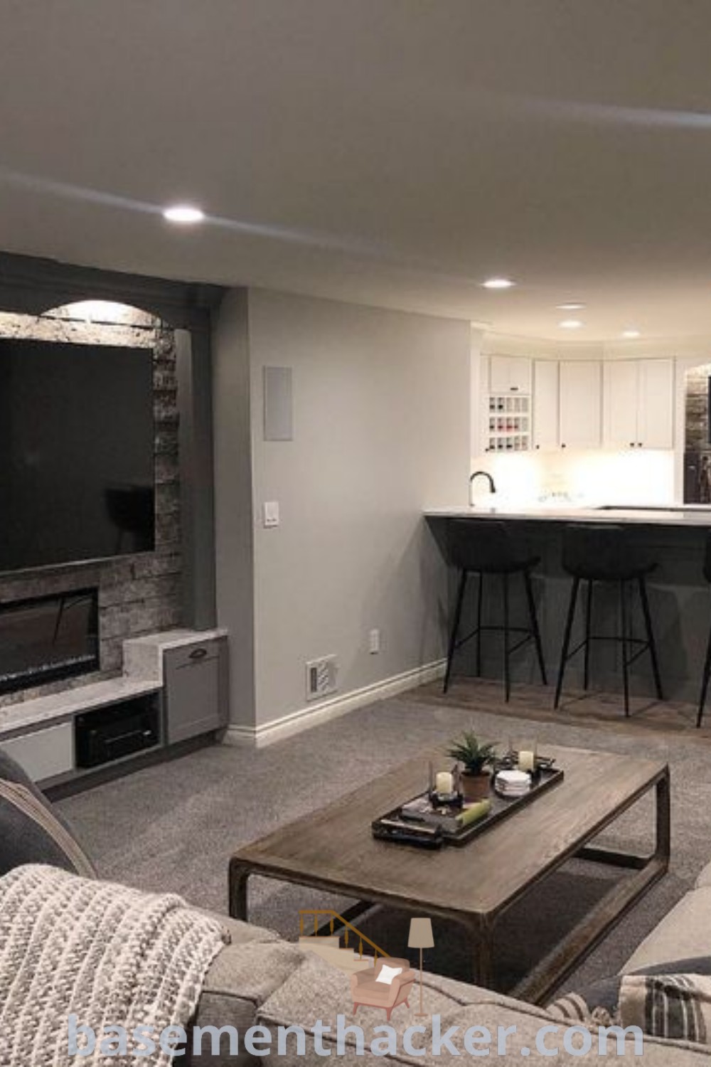 A beautifully decorated living room filled with modern furniture and a flat screen TV above a fireplace in a finished basement. This cozy and inviting space illustrates innovative ideas for a stylish bonus room design, highlighting the best basement remodeling ideas. Explore more tips at basementhacker.com.