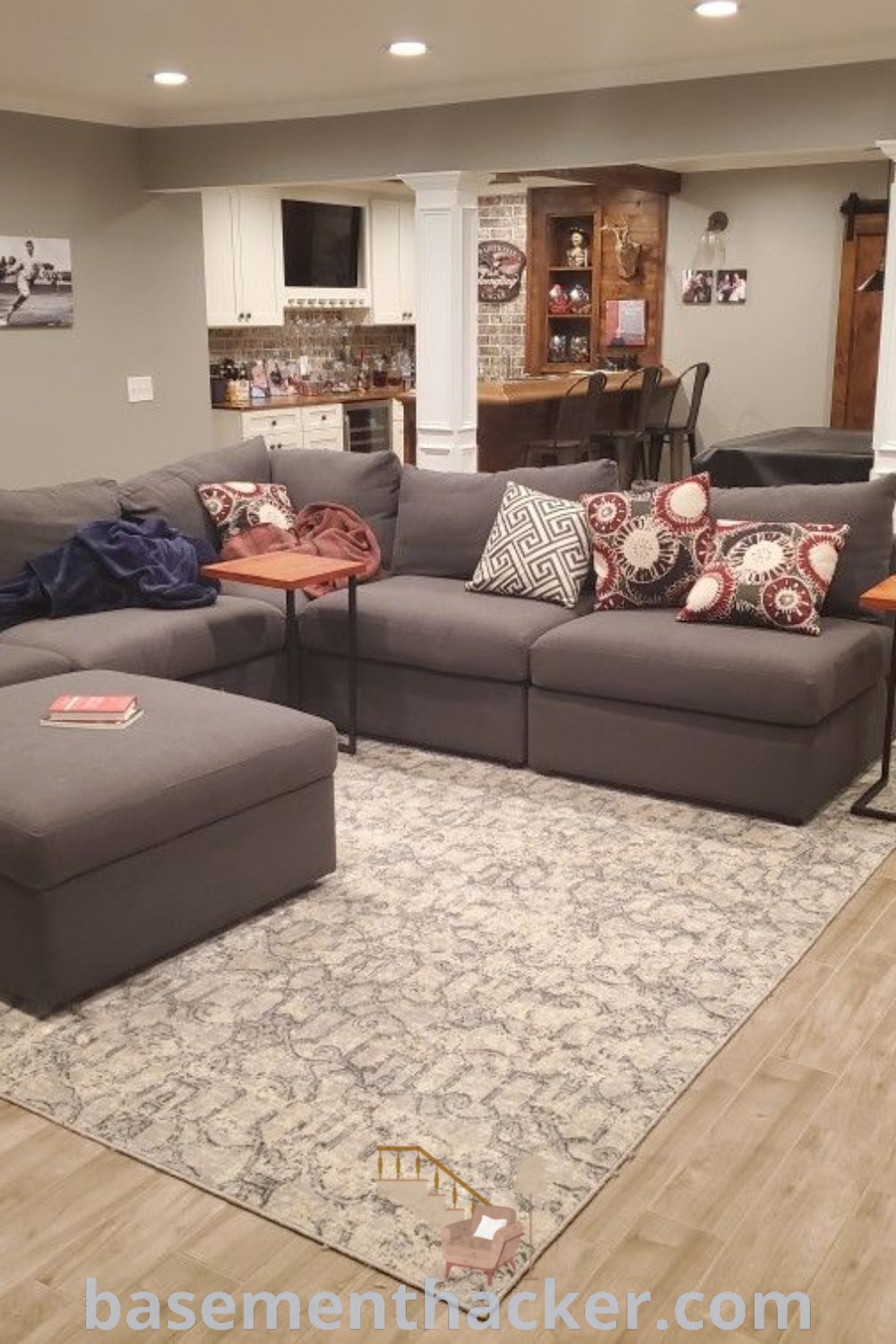 A stylish basement sitting area filled with furniture and a staircase, adorned with warm colors and decor ideas for ultimate entertaining. Discover amazing basement living rooms and finishing ideas at basementhacker.com.