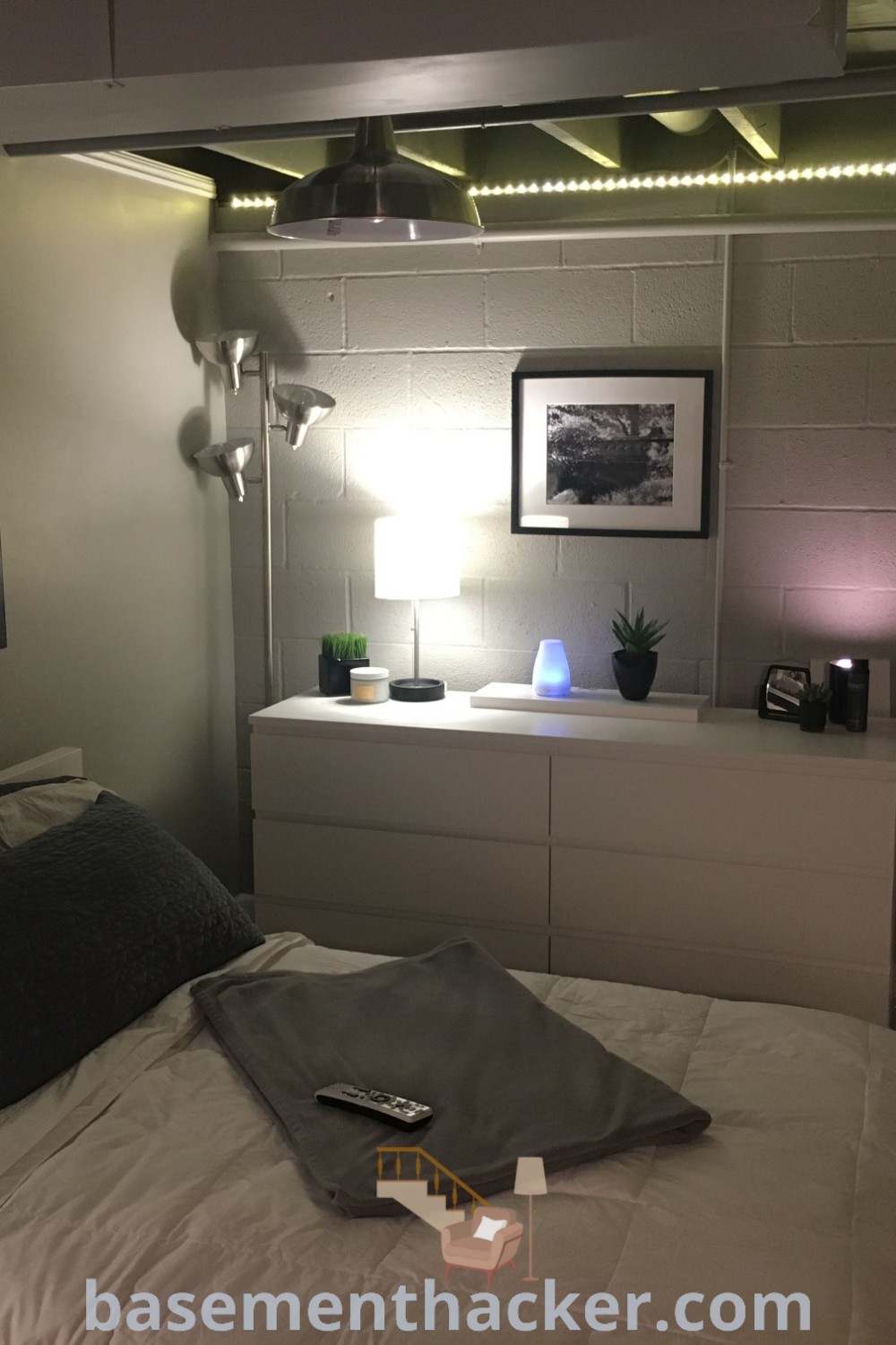 A stylish basement bedroom with a cozy bed, dresser, and wall art, showcasing innovative ideas for a functional and aesthetic space at basementhacker.com. Explore cool basement bedroom ideas and transformation tips for a stunning revamp to create a cozy retreat.