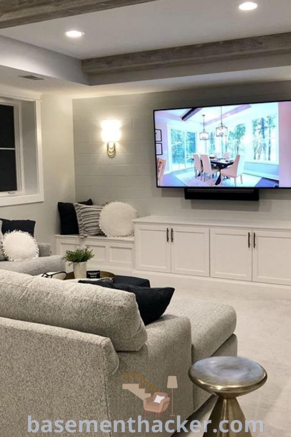 A charming basement living room filled with cozy furniture and a flat-screen TV mounted on the wall, showcasing innovative basement makeover ideas for a stylish and functional home design. Perfect for family gatherings, this space embodies cozy family basement vibes and offers seamless media room design ideas. For more inspiration, visit basementhacker.com.