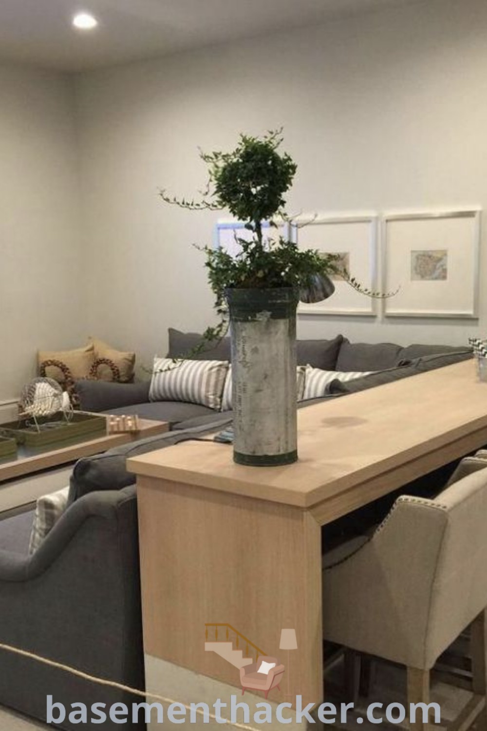 A cozy basement living room filled with furniture, a flat-screen TV mounted to the wall, and stylish decor behind the couch. This space showcases best basement remodeling ideas and innovative designs for an ultimate entertaining area. Explore more stylish bonus room design ideas for families at basementhacker.com.