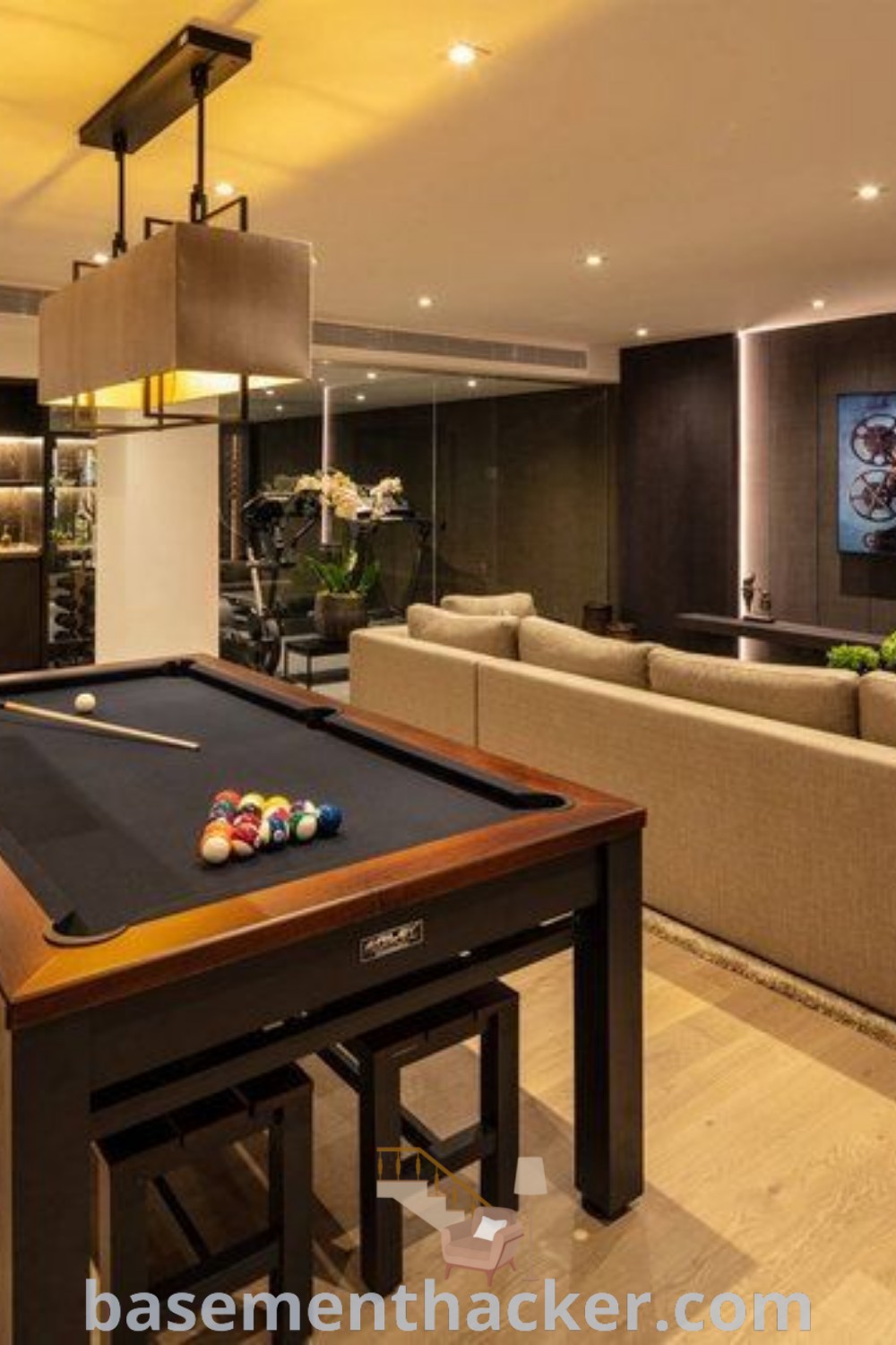 A stylish pool table in a living room featuring couches and a television, showcasing design ideas for small game rooms and basement living. This inviting space is perfect for ultimate entertaining, providing innovative basement makeover ideas for a stunning revamp. Explore more at basementhacker.com.