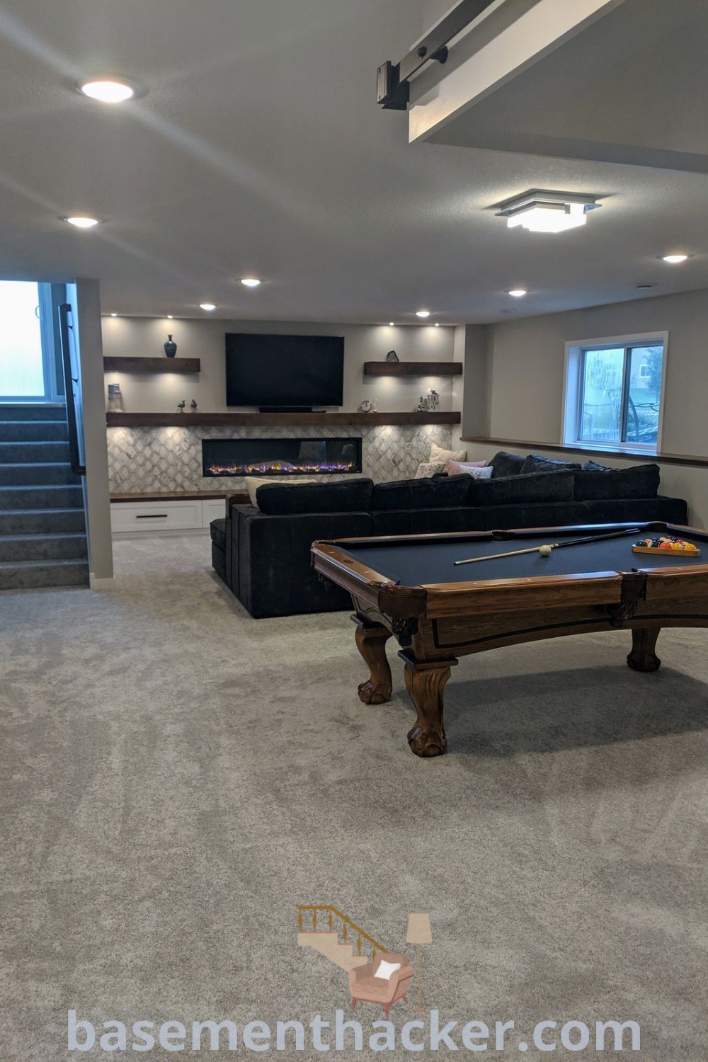 A modern basement game room showcasing a pool table, situated in a chic living room enhanced by stairs, offering stylish and functional decor ideas for families. Explore more on basementhacker.com for innovative basement makeovers and decoration inspiration.