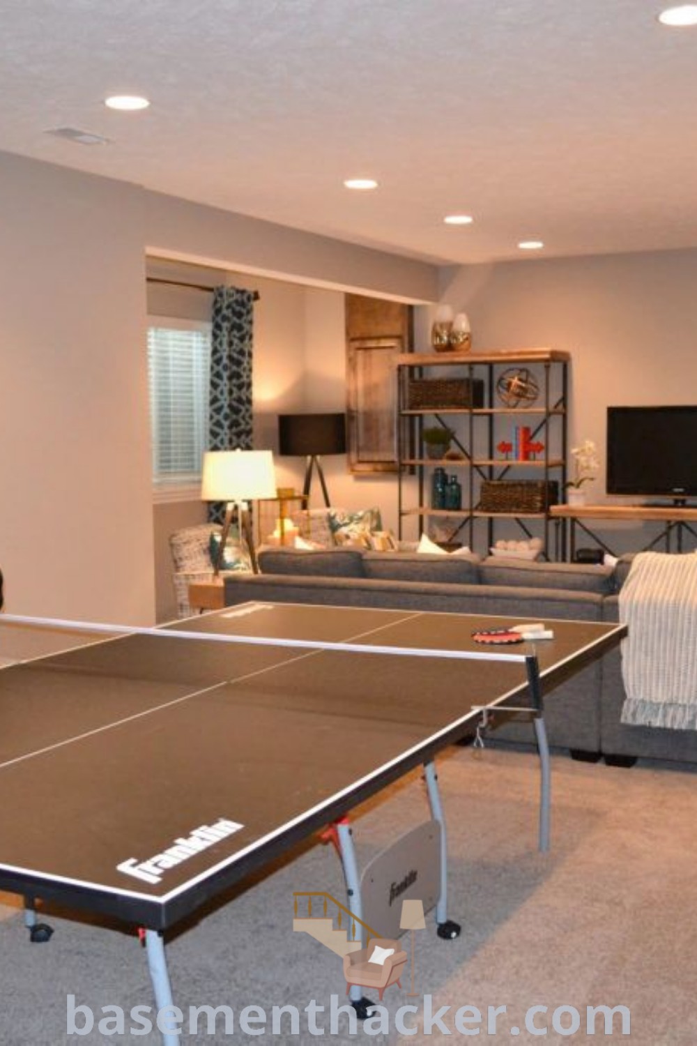 A vibrant living room in the basement filled with furniture and a ping pong table, showcasing innovative ideas for designing a stylish bonus room that encourages fun and relaxation. Discover the best basement remodeling ideas for your home at basementhacker.com.