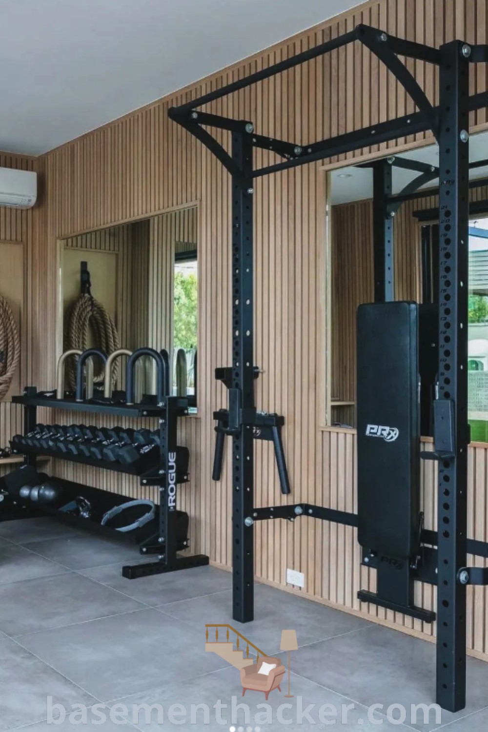 A stylish home gym in a basement featuring mirrors and workout equipment, showcasing innovative ideas for designing a functional space. This basement workout room offers the best basement remodeling ideas for creating a cozy and organized home gym. Find more inspiration at basementhacker.com.