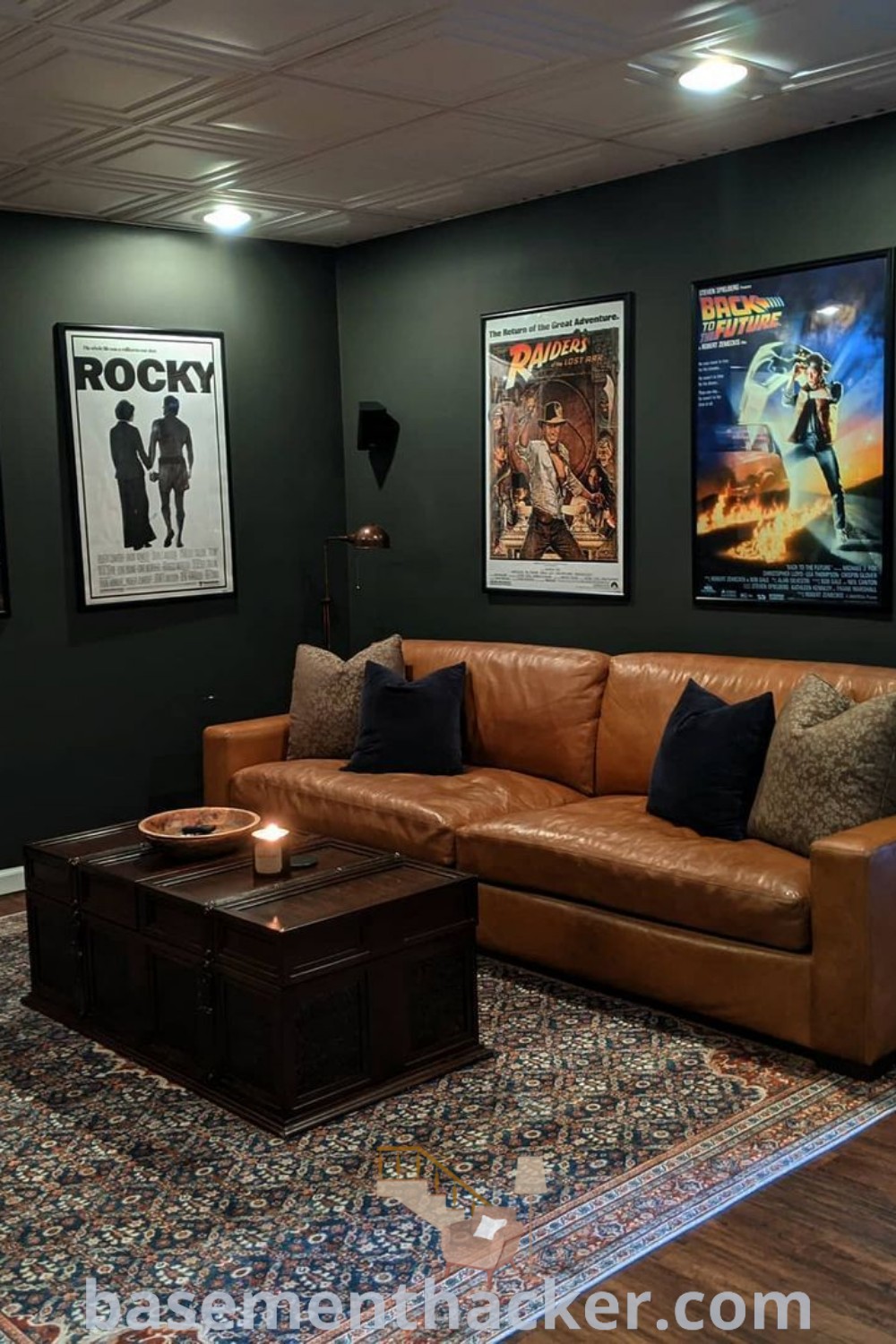 A cozy basement living room featuring comfortable furniture and colorful posters on the wall, showcasing innovative ideas for a stylish and functional home design. This space is perfect for ultimate entertaining, with creative basement colors and decoration tips available at basementhacker.com.