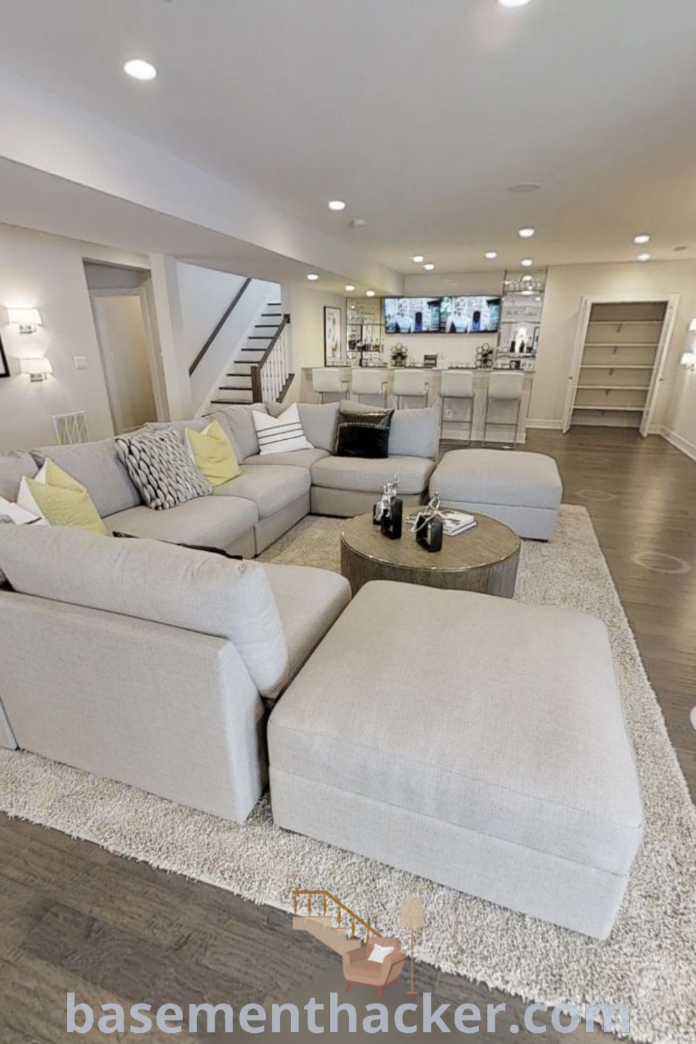 A living room with furniture and a fireplace next to a staircase, designed for a cozy and organized home ambiance. This space embodies innovative basement makeover ideas for stunning basement designs that the whole family will enjoy. Explore stylish bonus room design ideas at basementhacker.com.