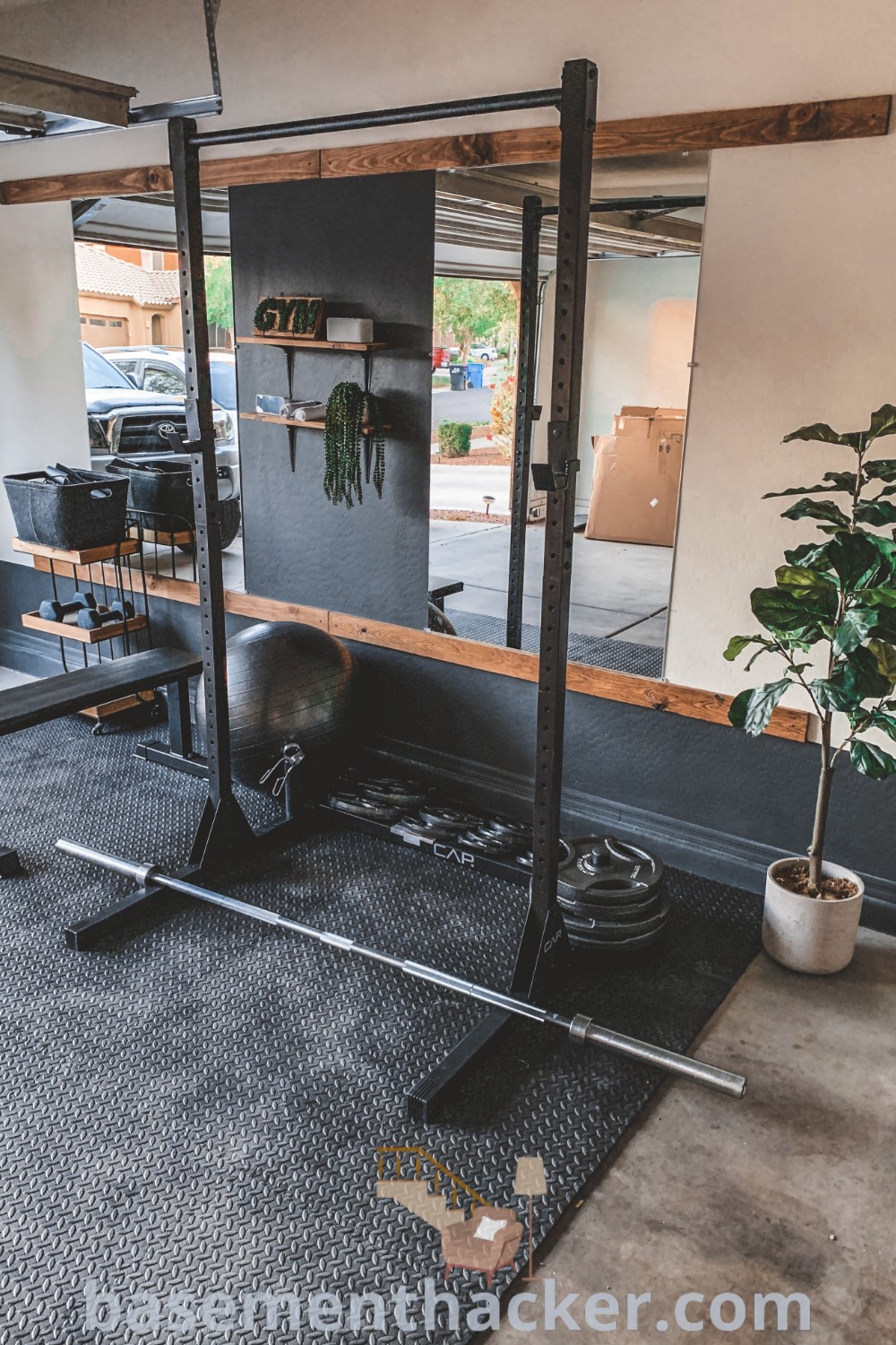 A stylish home gym in a basement featuring workout equipment, a potted plant, and DIY garage storage cabinets for a cozy and organized workout environment. Discover innovative ideas for designing your own dream home gym at basementhacker.com.