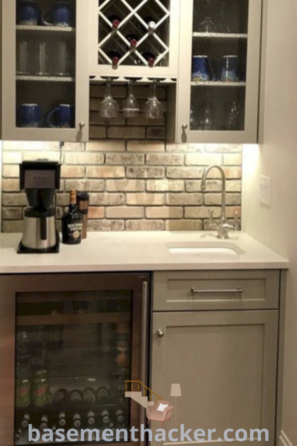 A small kitchen showcasing white cabinets and grey countertops, with a built-in wine bar nook featuring wine glasses on shelves. This space reflects innovative ideas for designing a stylish and functional home, perfect for ultimate entertaining. For more inspiration, visit basementhacker.com.
