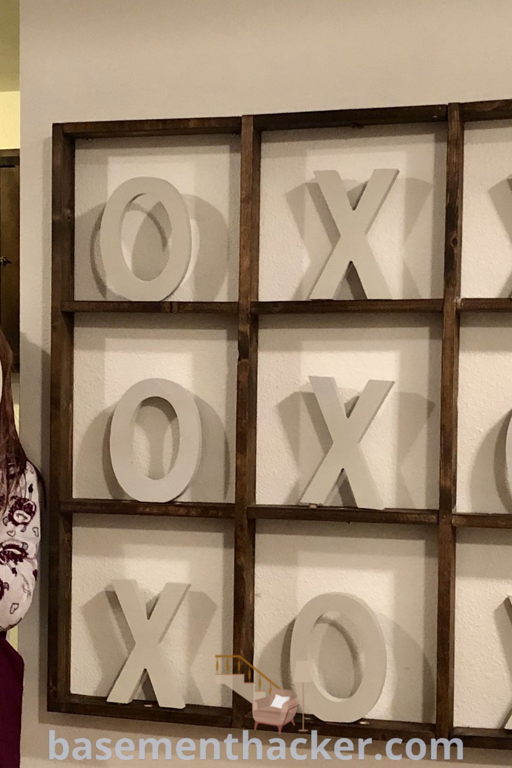 A woman holding a magnifying glass in front of an xoxo sign, showcasing innovative ideas for designing a stylish game room. This image is perfect for inspiration on basement makeovers and family game room decor ideas. For more creative inspirations, visit basementhacker.com.