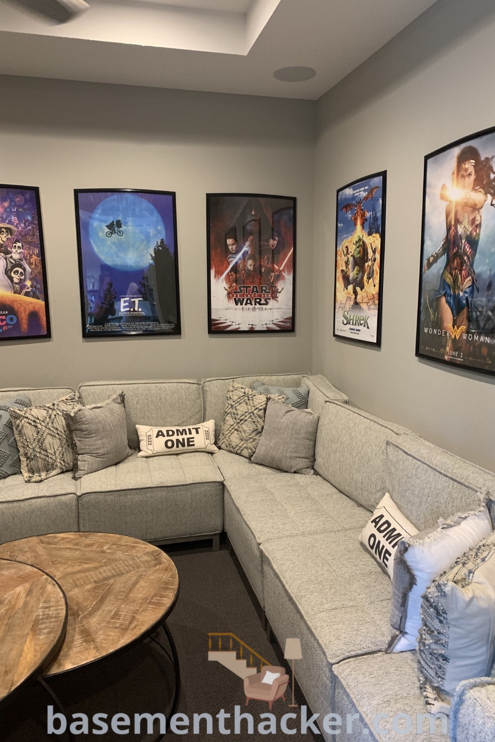A cozy living room filled with furniture, pictures above the couch, showcasing movie theme home decor ideas for a stylish bonus space. This setup includes innovative loft sectional ideas, perfect for family gatherings or small office hangouts. Explore more at basementhacker.com.
