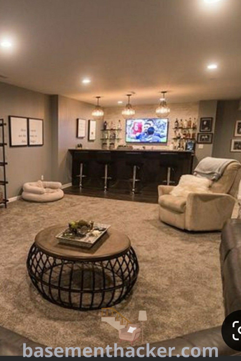 A stylish basement living room filled with furniture and a flat-screen TV mounted on the wall, ideal for ultimate entertaining. This design showcases innovative ideas for a cozy and organized home, perfect for families and individuals alike. Explore more basement remodeling ideas at basementhacker.com.