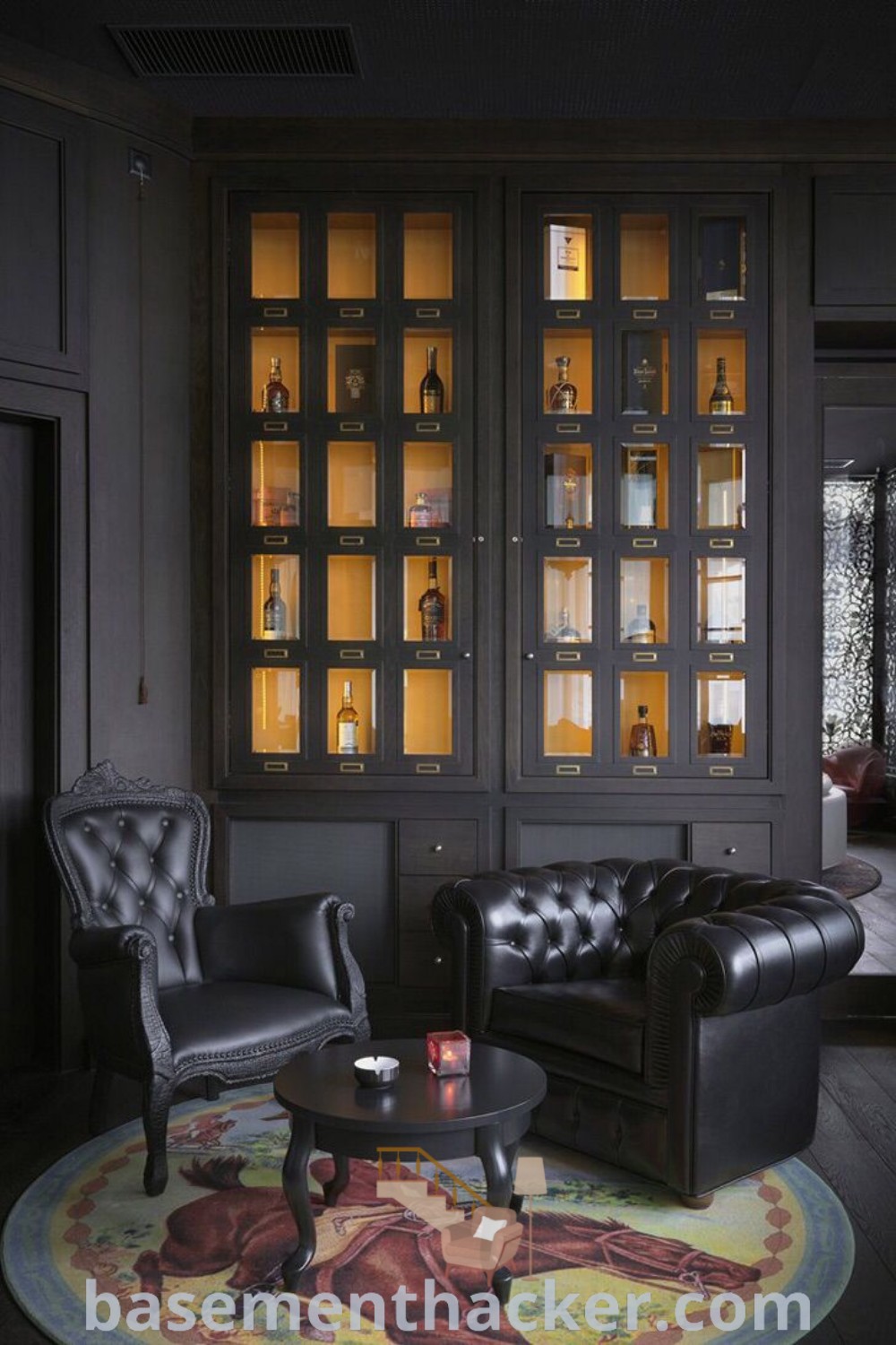 A chic living room filled with black furniture and shelves, designed as a whisky lounge for ultimate entertaining. This space showcases innovative ideas for designing a cozy basement, featuring a whisky bar and elements of a stylish and functional home. Discover more unique basement design ideas at basementhacker.com.
