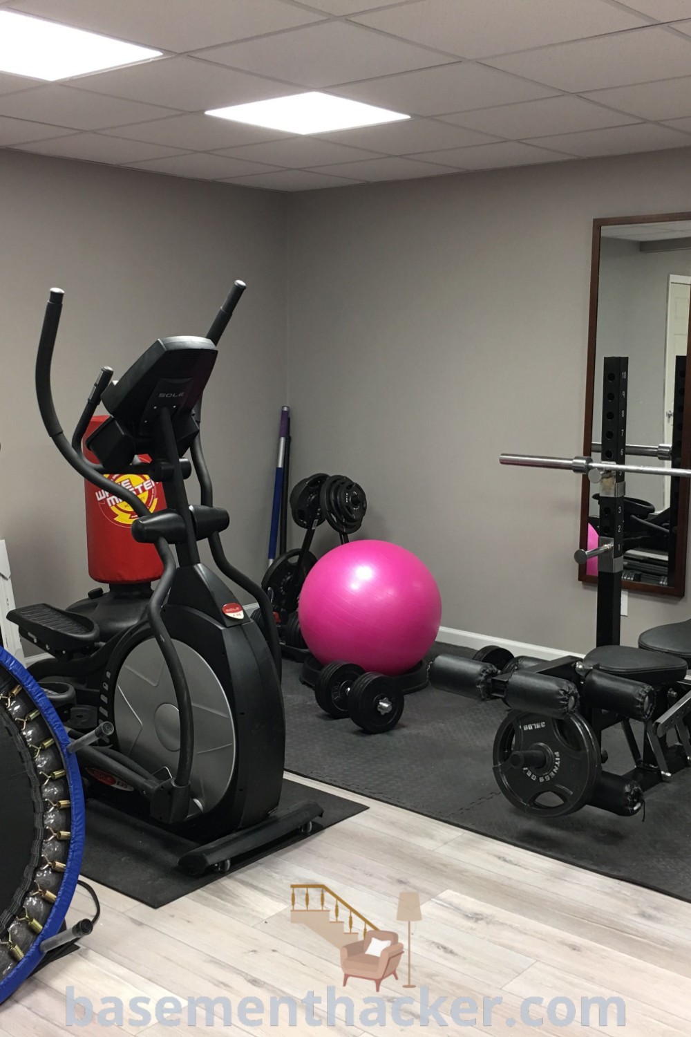 A stylish half garage gym equipped with exercise equipment and mirrors, offering innovative ideas for designing a functional home exercise room. Ideal for maximizing space, this gym design integrates elements from basementhacker.com, making it an inspiring example of small gym design perfect for active lifestyles.