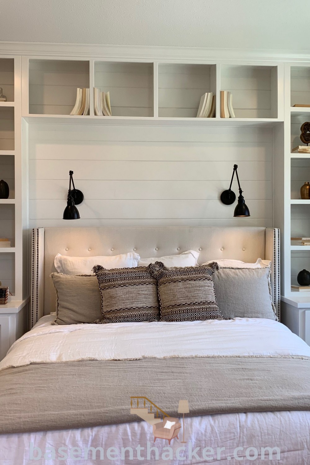A beautifully designed bedroom with built-ins behind the bed, featuring shelves for the headboard and a spacious king-size bed wall unit. This setup offers stylish storage solutions and innovative ideas for designing a cozy and organized home. Discover more design inspiration at basementhacker.com.