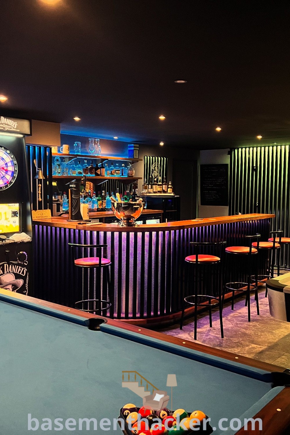 A stylish pool table in a modern billiard bar room illuminated by neon lights with stools around it, showcasing innovative ideas for designing a home sports bar and creating an awesome game room setup. Explore more design ideas at basementhacker.com.