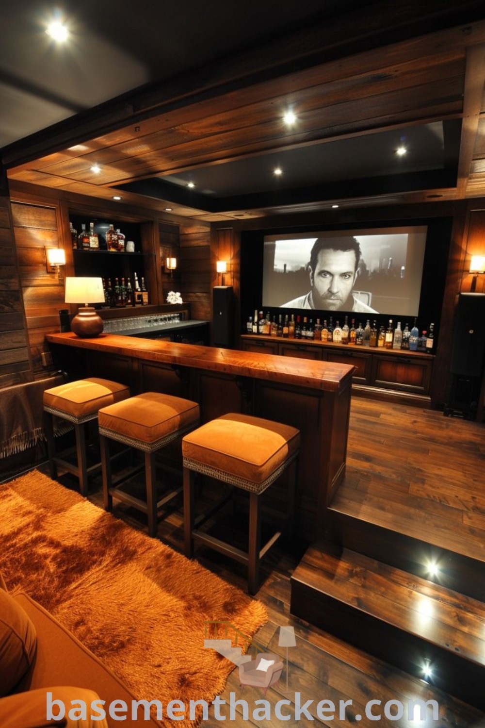 A stylish home bar with stools and a large screen on the wall, showcasing innovative ideas for designing an underground cinema room. This man cave theater room offers the best in home entertaining, merging cinema and games for an inviting atmosphere. Discover more stylish home design ideas at basementhacker.com.