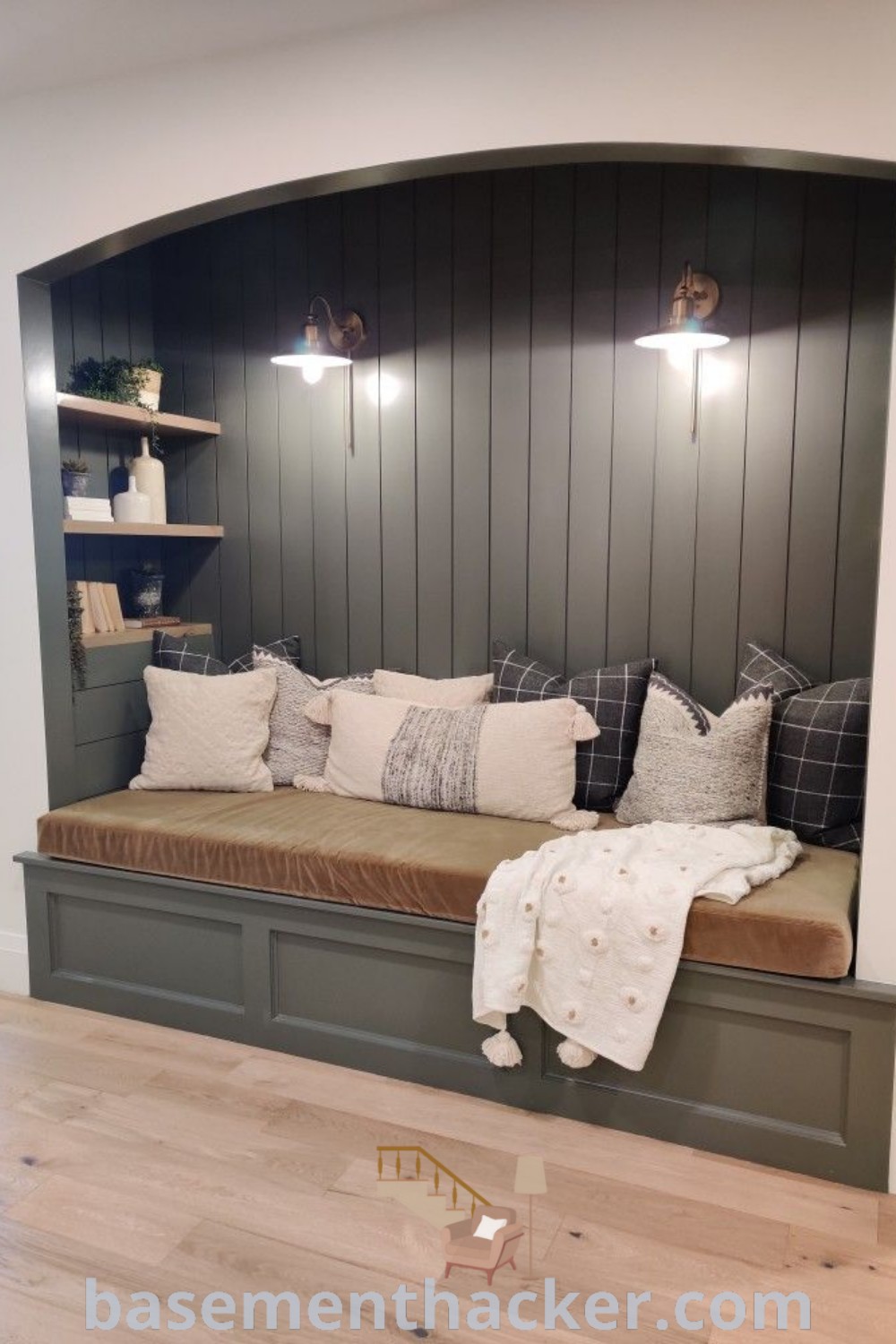 A cozy bench with pillows and blankets in a room with wood paneling, offering innovative ideas for designing reading nooks and stylish bonus spaces. Discover more inspiration and design ideas for a cozy and organized home at basementhacker.com.