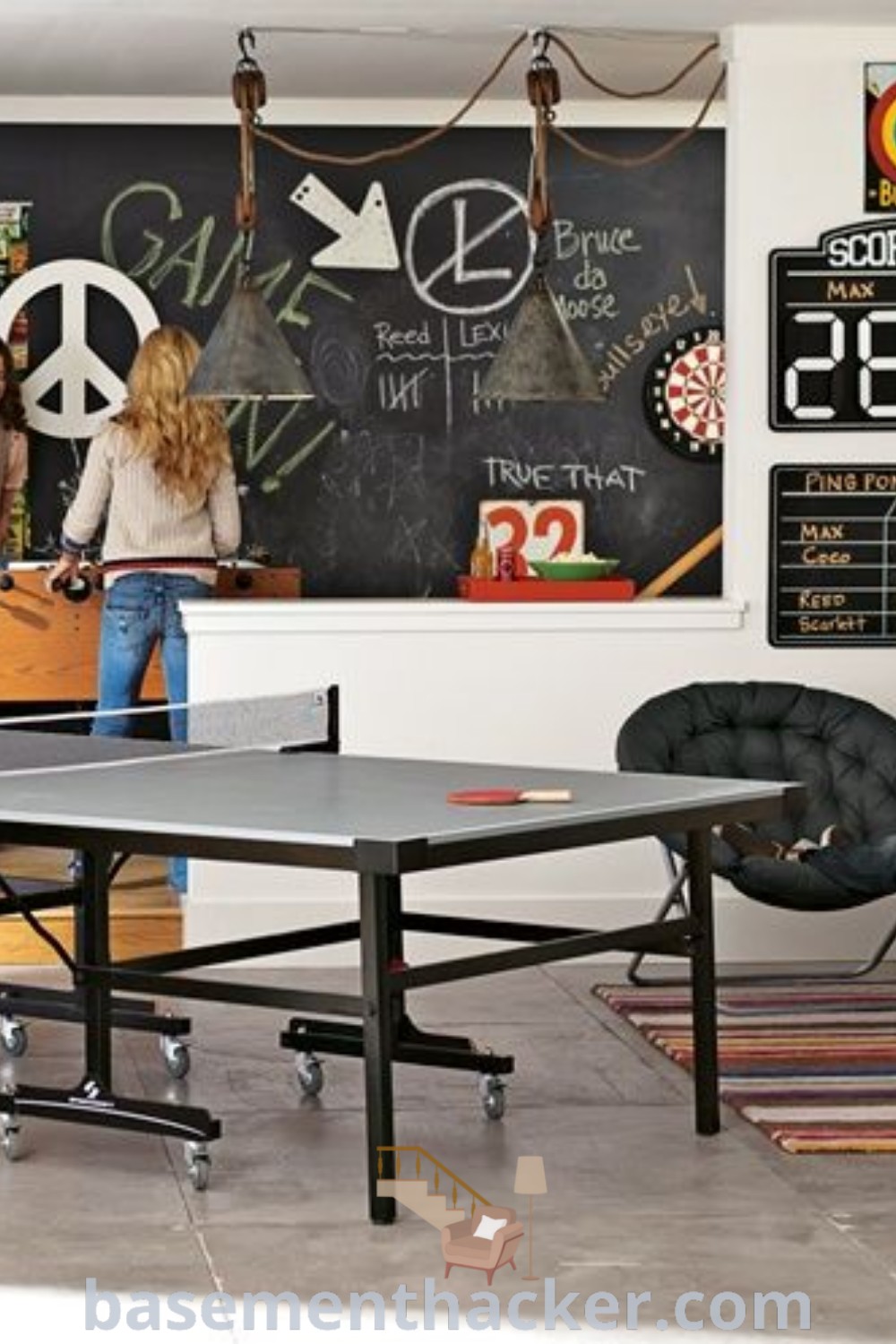 A cozy basement game room scene showing a man sitting next to a laptop on a table while a woman stands behind him. This image embodies innovative ideas for designing teen game rooms and stylish bonus spaces that are perfect for family entertainment. Discover more inspirations at basementhacker.com.