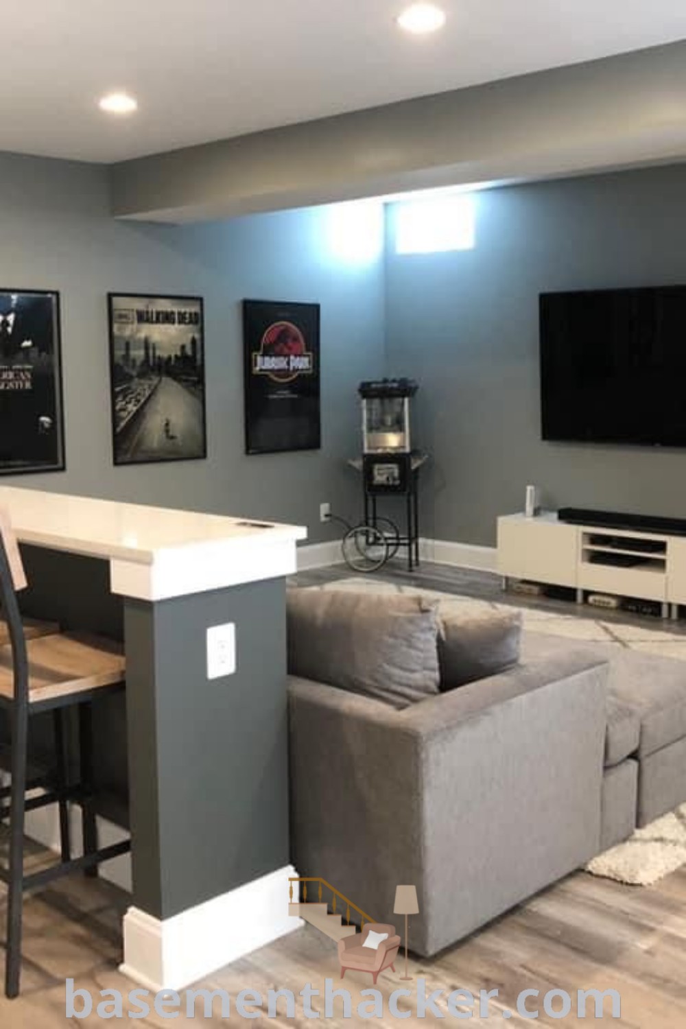 A stylish basement living room featuring a flat screen TV mounted on the wall, surrounded by comfortable furniture designed for ultimate entertaining. This space incorporates innovative ideas for designing a cozy and functional home, making it perfect for family gatherings and movie nights. Explore more design ideas at basementhacker.com.