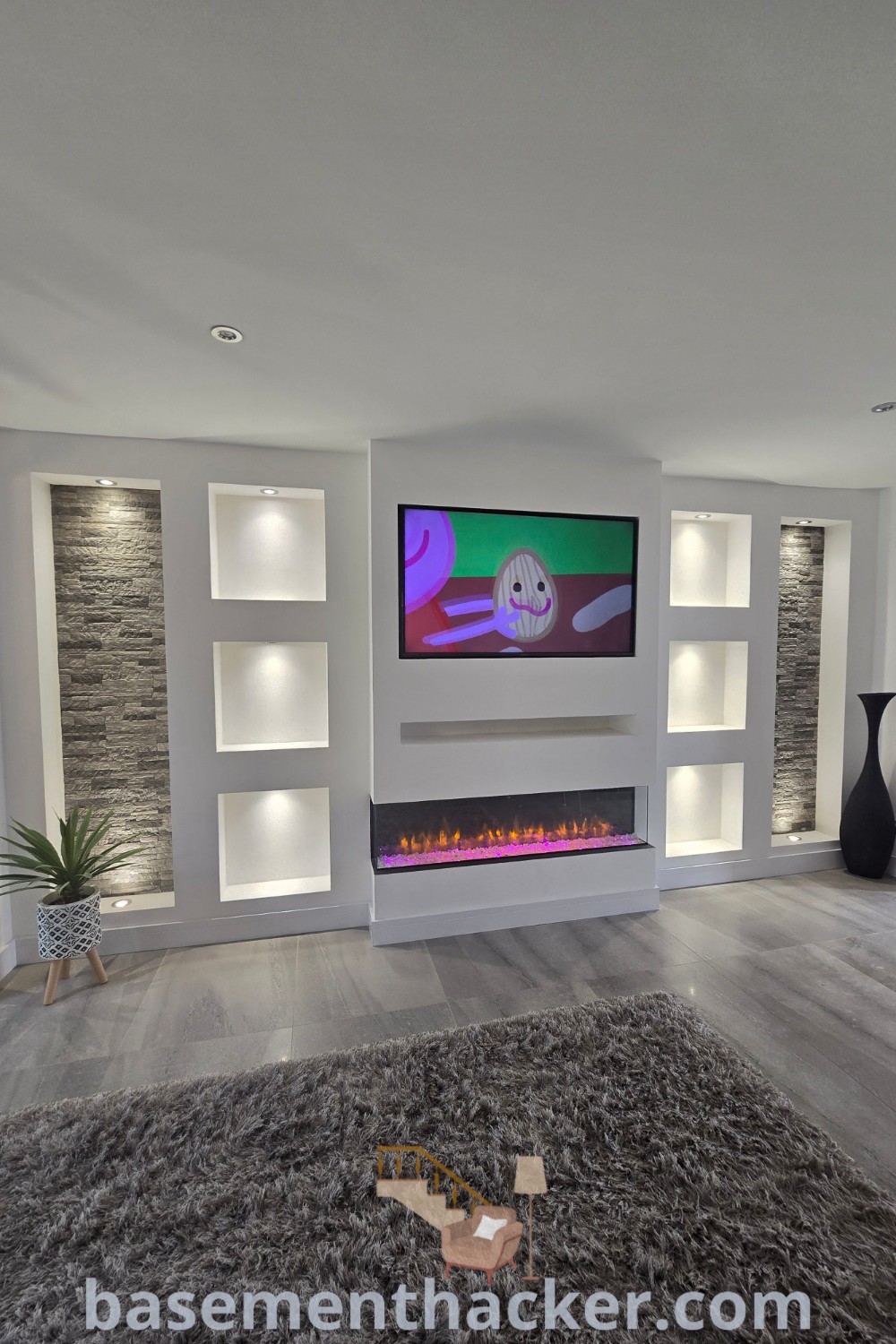 A cozy living room with a fireplace, modern entertainment center, and innovative fish tank in wall built-ins, showcasing stylish bonus room design ideas. This space blends modern gray living room aesthetics with a brick wall TV unit design, offering functional decor tips for remodeling. More inspiration available at basementhacker.com.