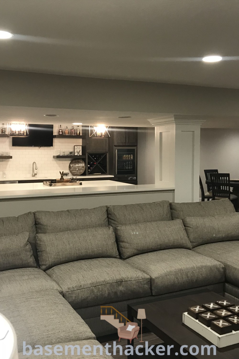 A stylish living room filled with furniture next to a modern kitchen, showcasing innovative basement makeover ideas for creating the ultimate entertaining space. Enhance your home with decor tips from basementhacker.com that turn your basement into a cozy and organized haven.