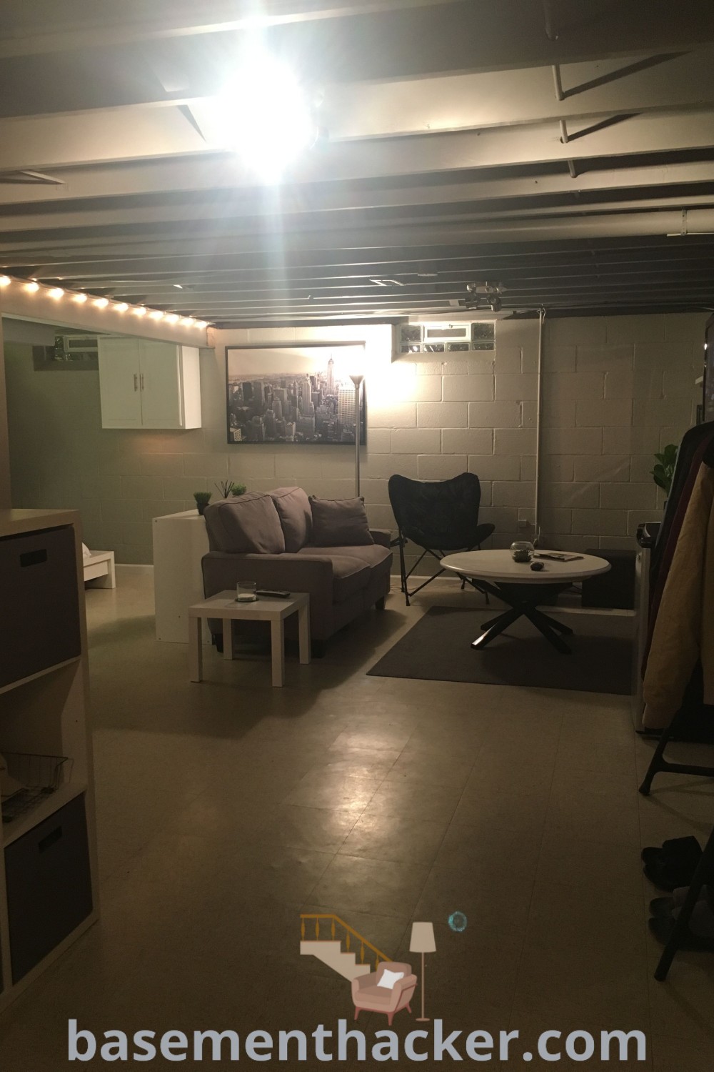 A cozy living room in an unfinished basement creatively showcasing various stylish bonus room design ideas for families, including innovative basement makeover ideas for a stunning revamp. This room is designed for ultimate entertaining, featuring furniture and lights, and provides inspiration for DIY small basement ideas. Discover more design tips at basementhacker.com.