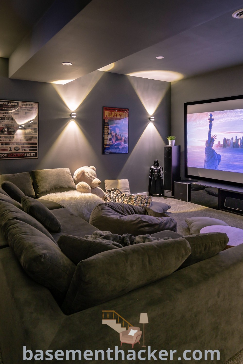 A living room featuring comfortable couches and a large screen, designed as a stylish home theater room. This space offers innovative ideas for designing an at-home movie theater, showcasing the best basement remodeling ideas for family entertainment. Discover more inspiration at basementhacker.com.
