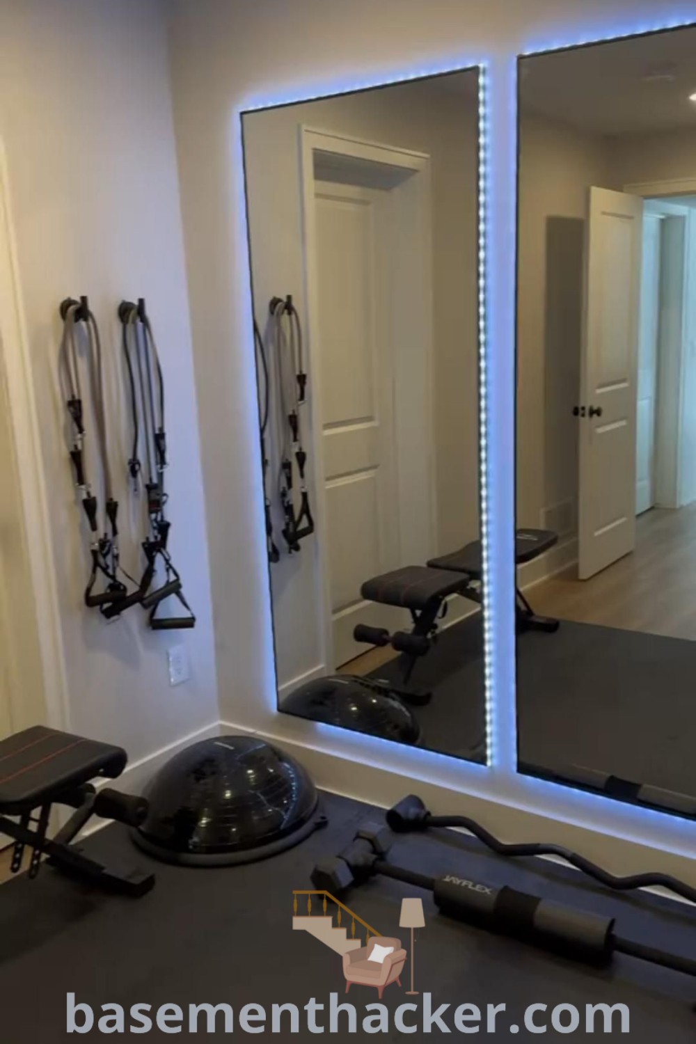 A small basement gym designed for ultimate convenience and style, featuring at-home gym equipment, a gym mirror for selfies, and aesthetic decor ideas. This innovative space from basementhacker.com showcases small gym room ideas to enhance your workout experience while maximizing space effectively.