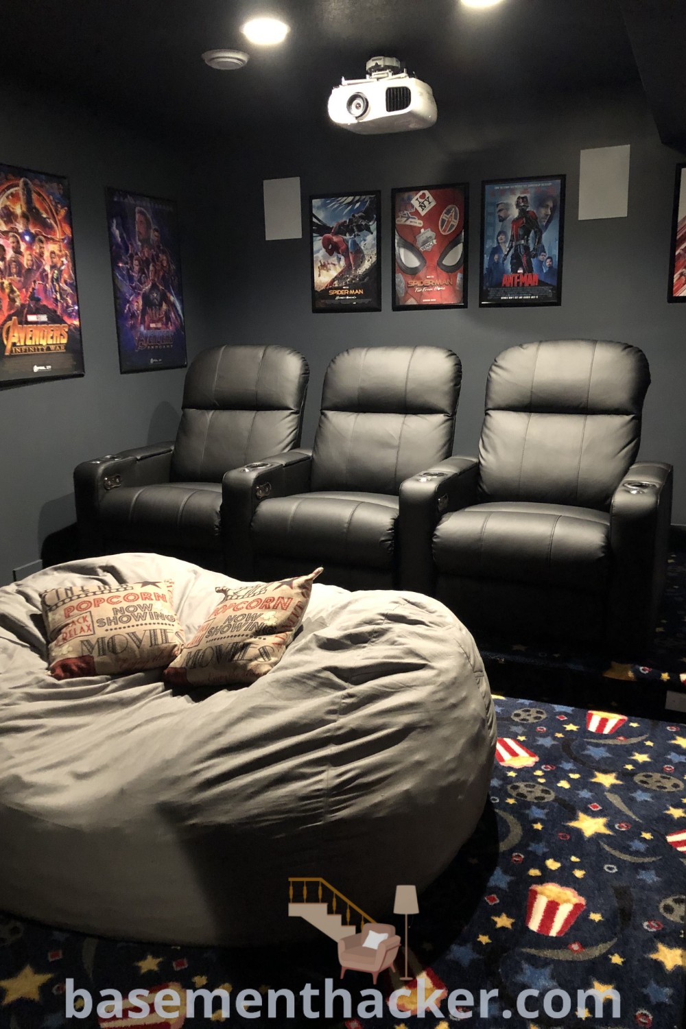 A cozy movie room setup with a large bean bag chair in front of two recliners, showcasing innovative ideas for designing small movie theaters. Perfect for creating a comfortable and organized space, this layout provides best basement remodeling ideas for an inviting movie and game room. Find more design inspiration at basementhacker.com.