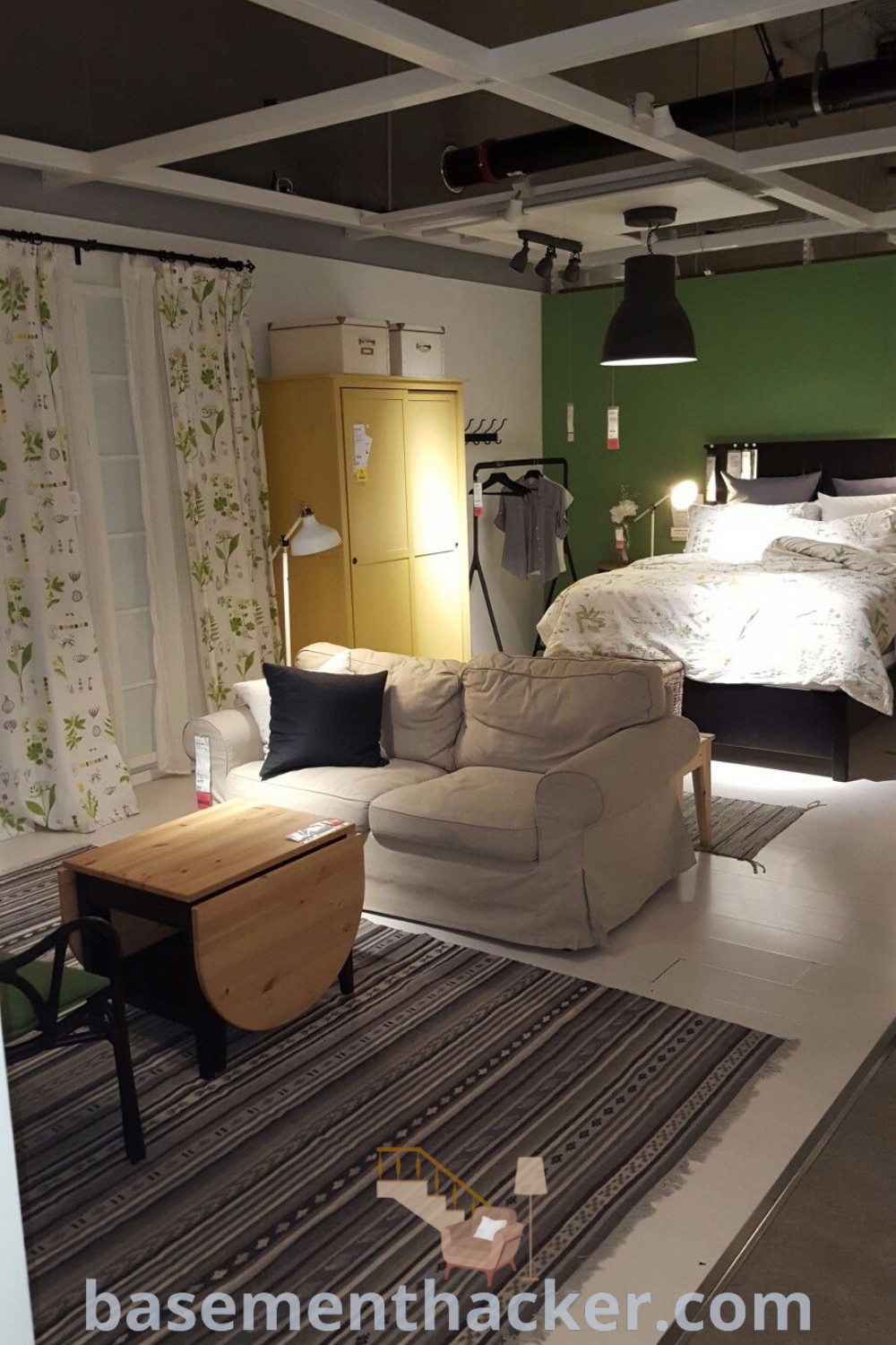 A cozy basement bedroom featuring a large bed and a couch, designed for ultimate entertaining. The space showcases innovative ideas for designing on a budget and offers stylish bonus room design ideas for families, making it a perfect cozy retreat. Find more inspirations for your basement makeover at basementhacker.com.