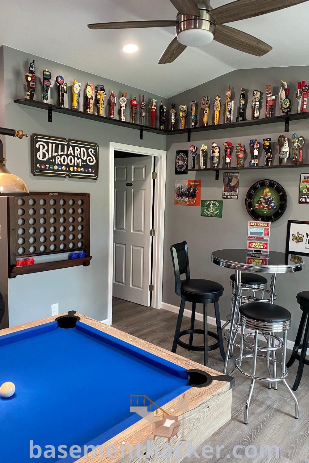 A beautifully designed billiards room featuring a pool table, bar stools, and shelves on the wall, ideal for creating a stylish bonus space at home. This basement game area showcases innovative makeover ideas for ultimate entertaining. Find more inspirations at basementhacker.com.