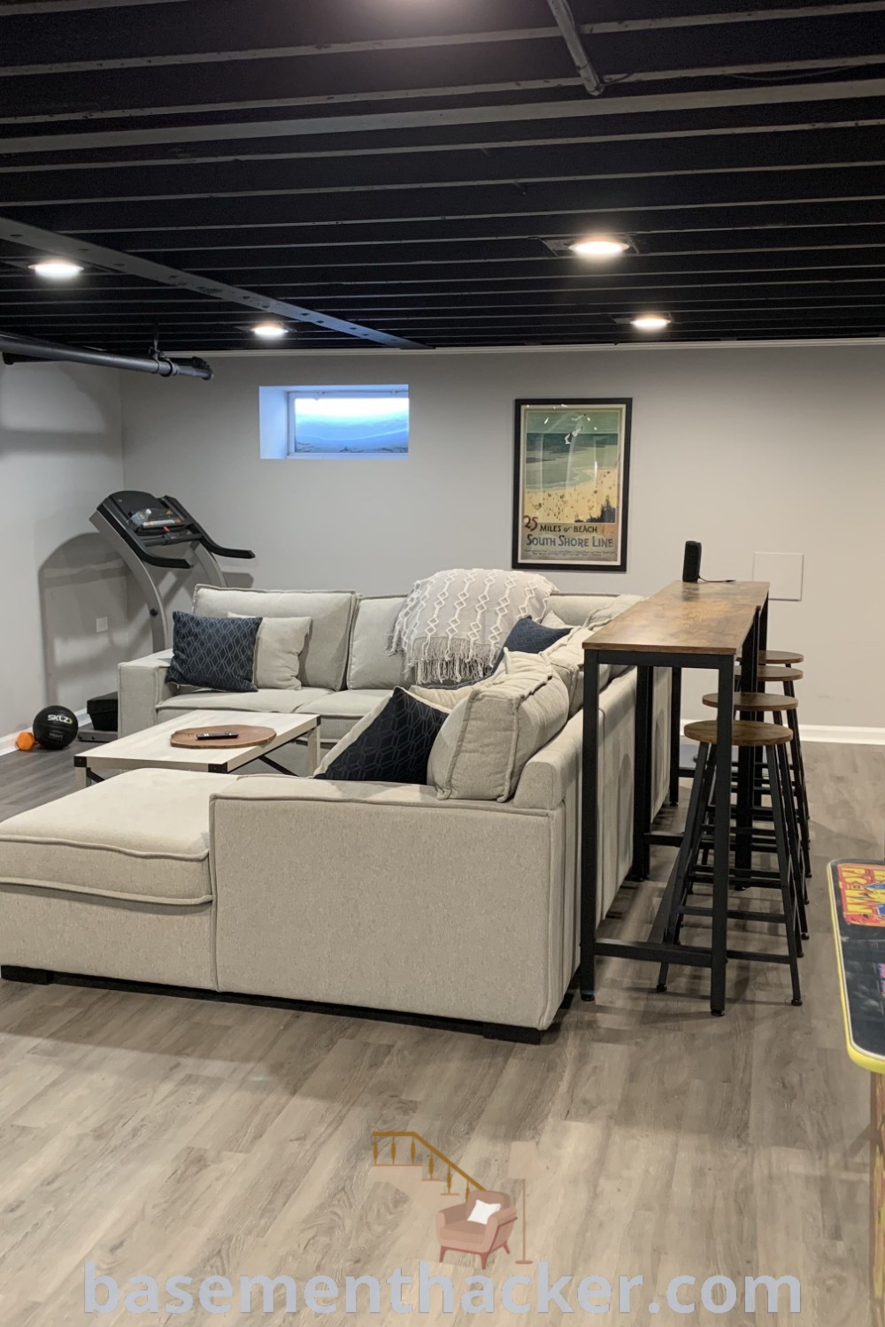 A stylish living room in a basement featuring a flat-screen TV, comfortable furniture, and innovative design ideas for a cozy and organized space. This area showcases awesome mens basement ideas and chill decor options, perfect for ultimate entertaining. Find more inspiration for designing your dream space at basementhacker.com.