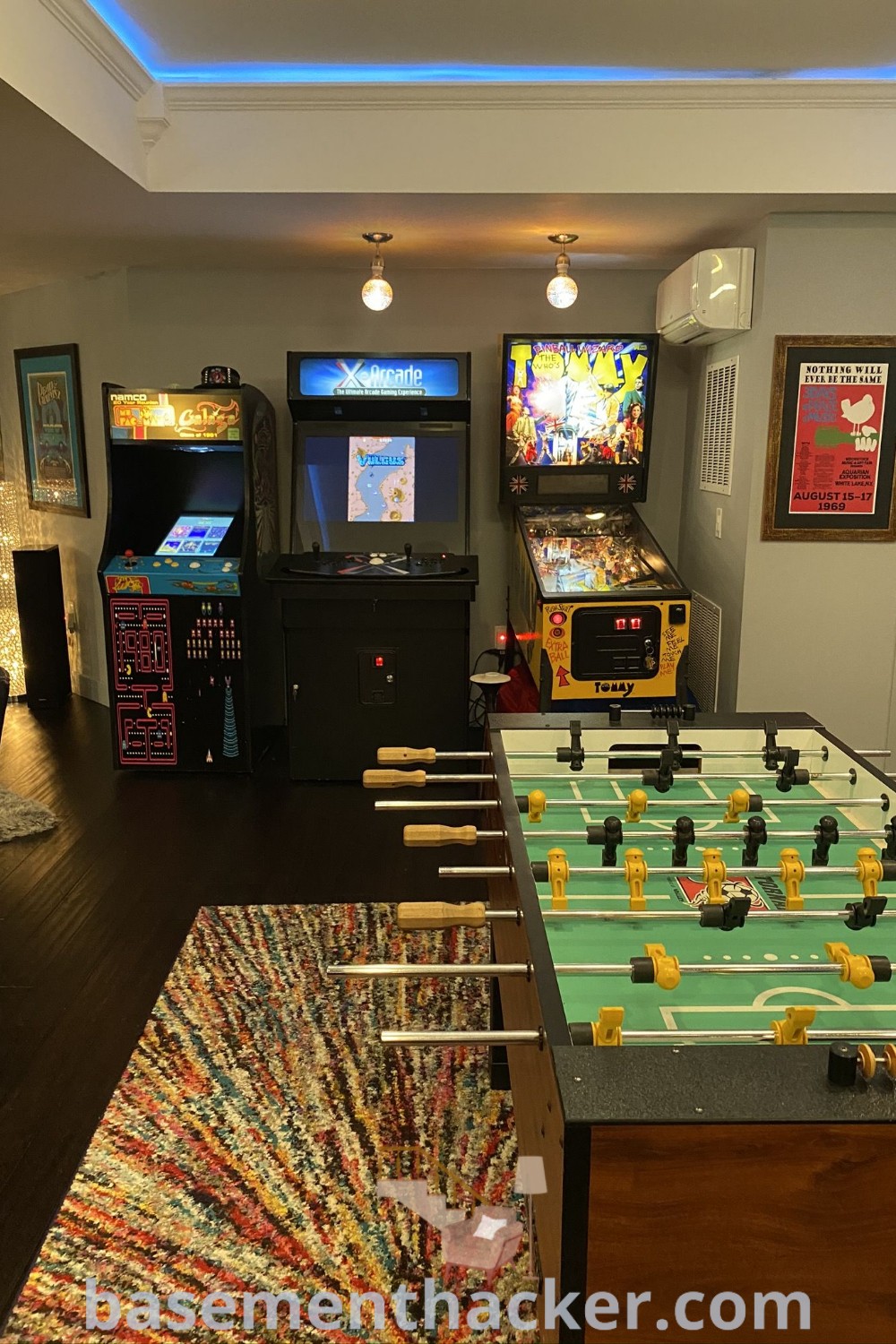 A vibrant game room featuring a stylish foo - o - mat, arcade machines, and video games on the walls, ideal for remodeling into an at-home entertainment space. Discover innovative ideas and design solutions for a cozy family-friendly arcade environment at basementhacker.com.