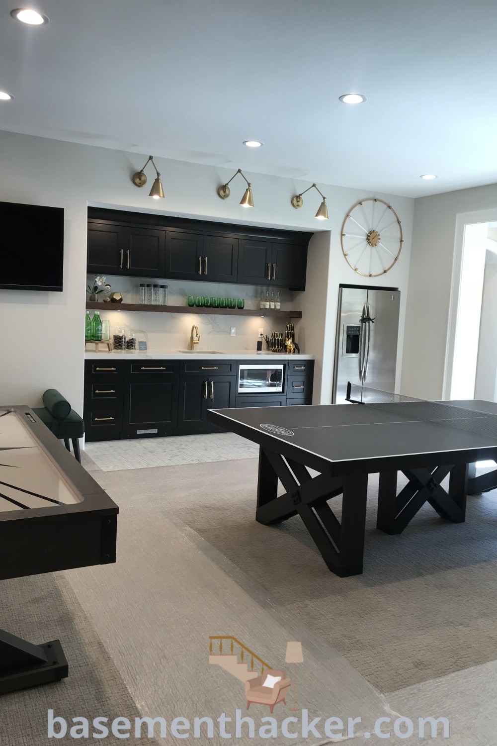 A stylish basement game room with a ping pong table and black cabinets, featuring modern farmhouse game room elements and wet bar possibilities. Perfect for a cozy and organized home, this setup offers innovative ideas for designing your ultimate entertaining space. Explore more at basementhacker.com.
