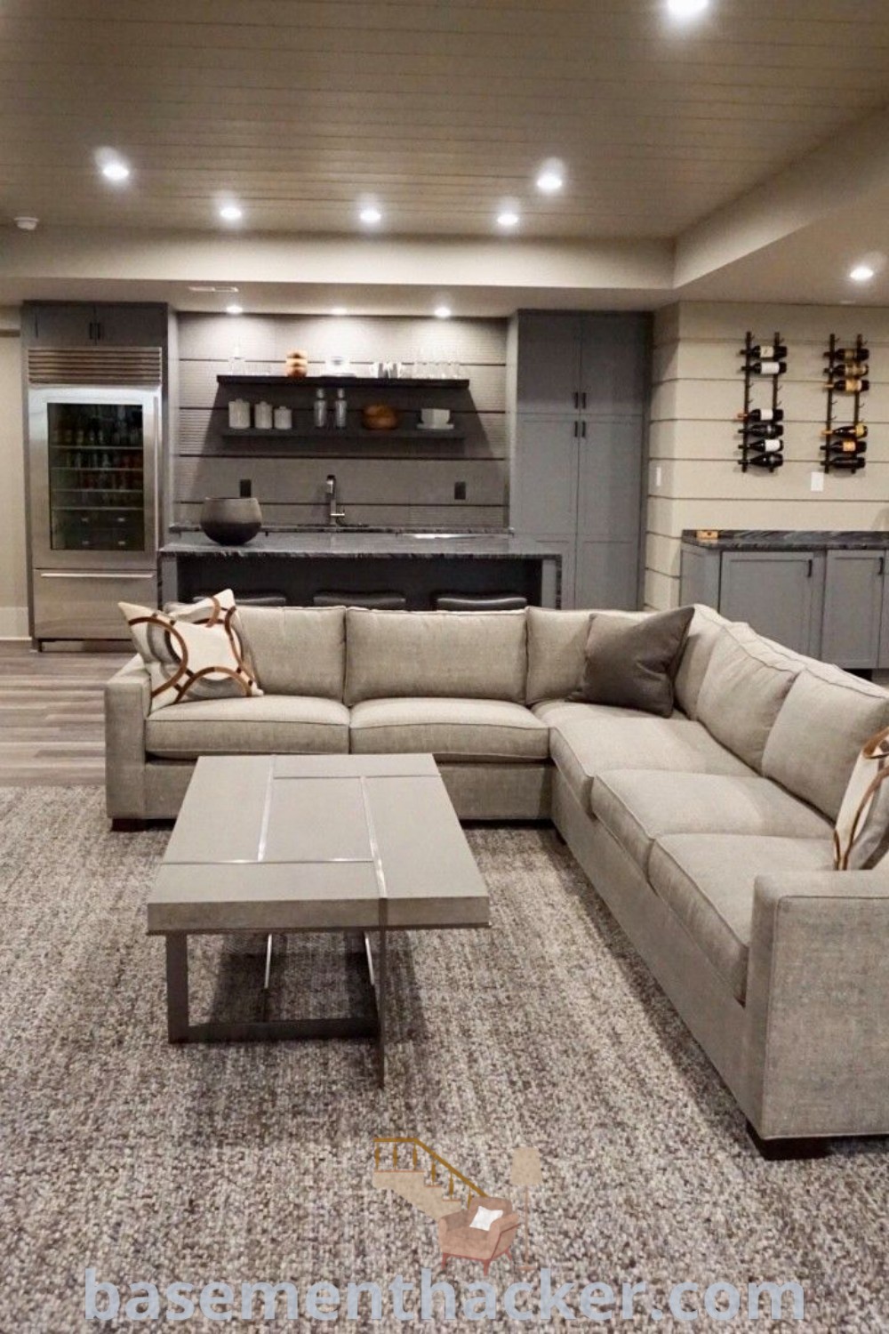 A cozy living room in a finished basement filled with stylish furniture, featuring a large flat screen TV mounted on the wall, showcasing awesome ideas for renovation and the best basement remodeling ideas for your home. Discover more basement decor inspiration at basementhacker.com.