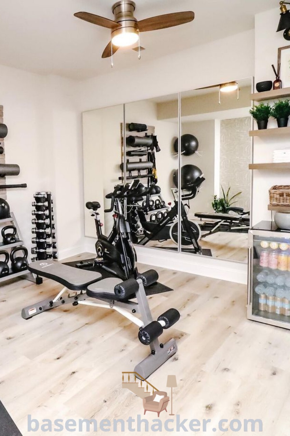 A modern home gym basement with exercise equipment, mirrors, and an inviting ambiance. This stylish basement offers innovative design ideas for creating a mini gym or wellness room, perfect for family workouts and relaxation. Explore more inspiring tips at basementhacker.com.