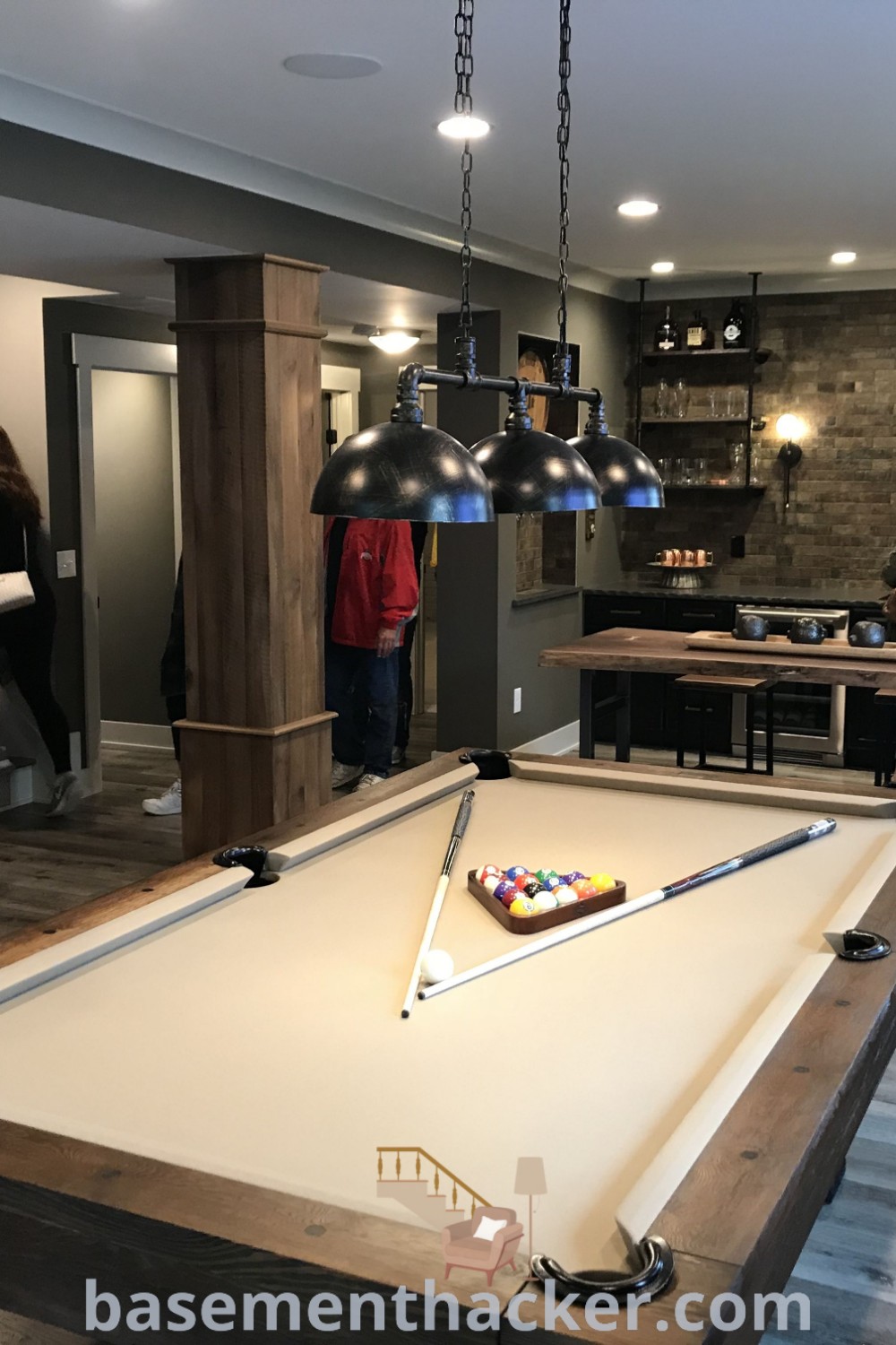 A lively basement bonus room featuring several people playing pool, showcasing innovative ideas for designing a functional and stylish space. Perfect for ultimate entertaining, this area blends modern home bar concepts with basement gym ideas. Discover more inspiration at basementhacker.com.