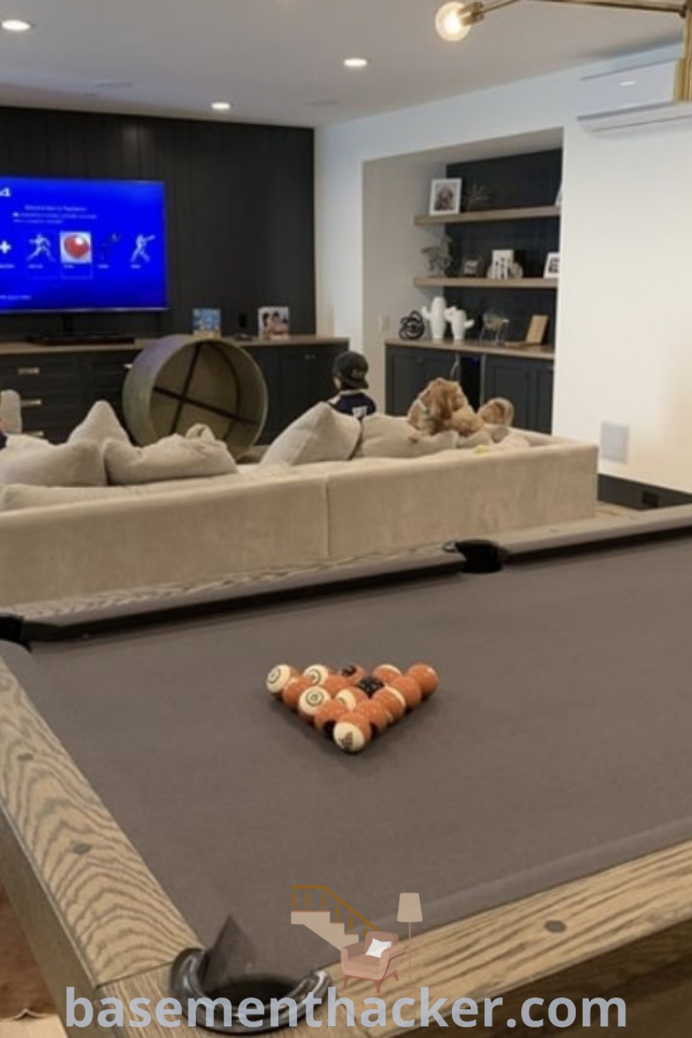 A living room with a pool table in the center, showcasing stylish decor ideas for a family-friendly basement game room. This space is designed for ultimate entertaining with a cozy and inviting atmosphere. Explore more innovative ideas at basementhacker.com.