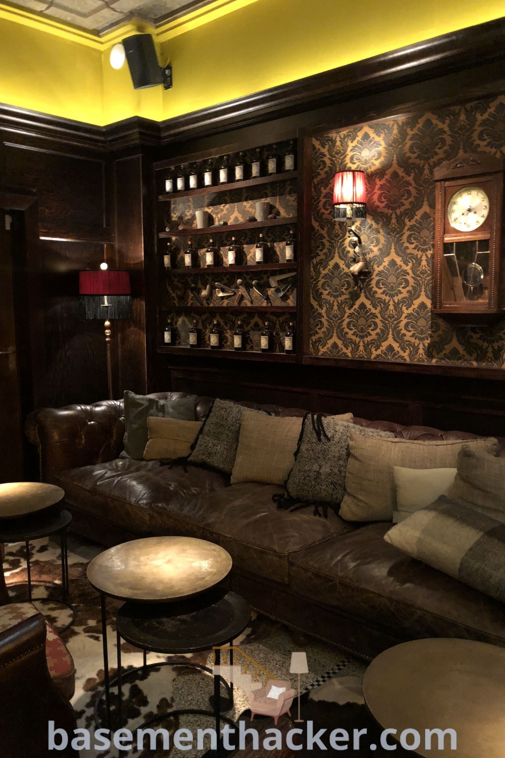 A cozy living room filled with furniture, showcasing a wall decorated with wine bottles, embodying speakeasy aesthetic vibes and innovative basement makeover ideas for stunning spaces. Explore more design inspirations at basementhacker.com.